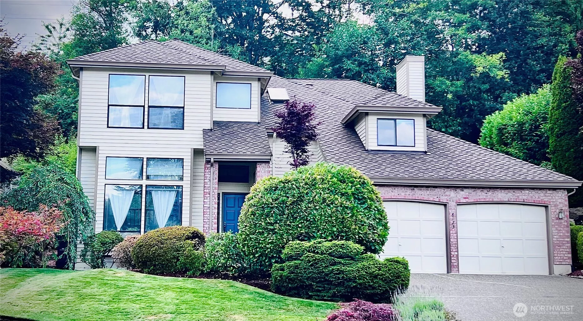 Front view of house with mature landscape & colors; two car garages with built shelves for storage