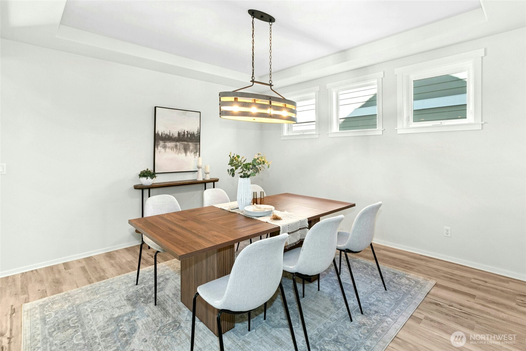 The large light filled dining room with cove ceilings is punctuated with a classic set of triple windows, graced with gorgeous millwork, and new chandelier.