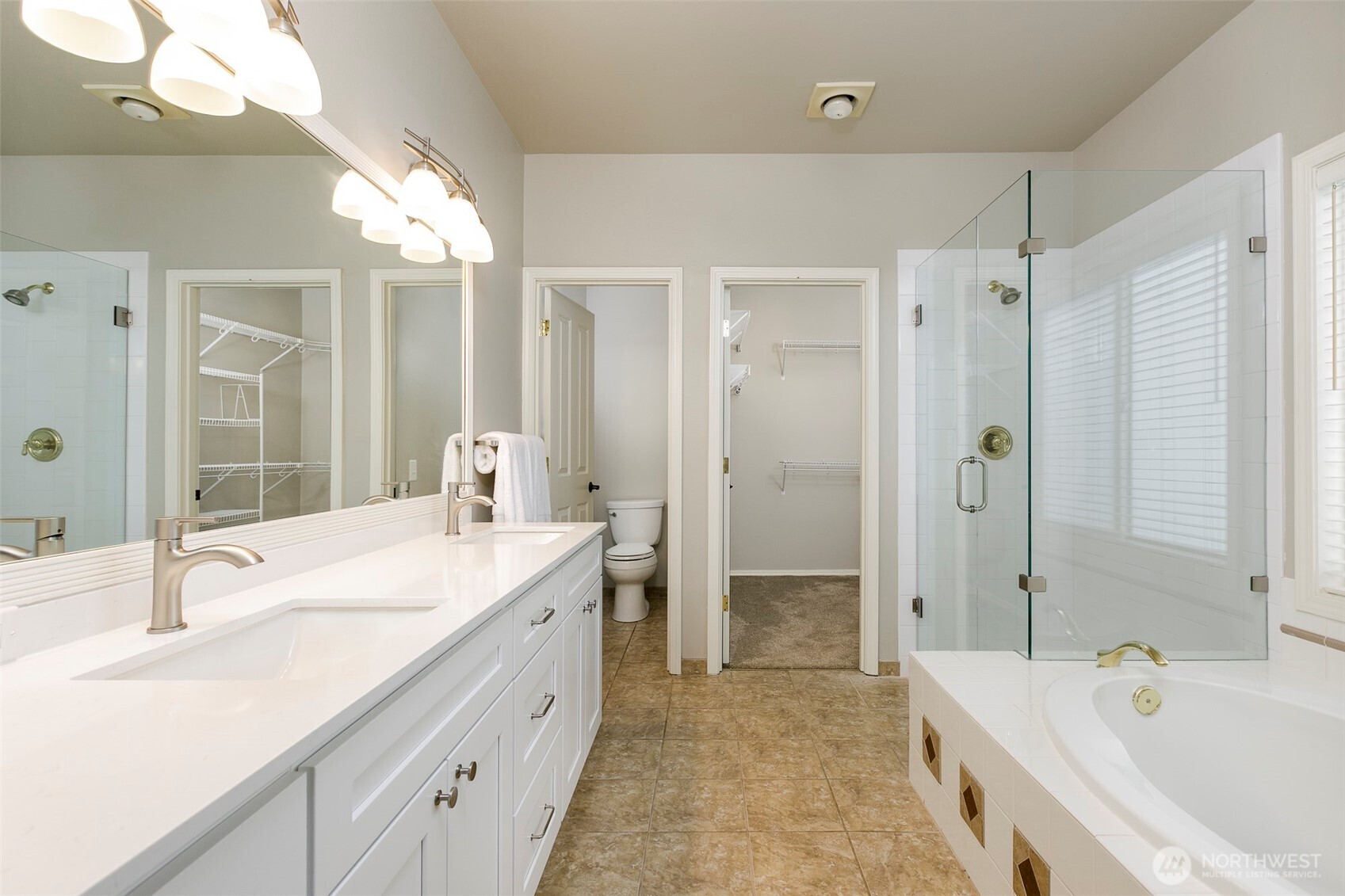 Updated primary bath w/ separate shower, soaking tub, new vanity w/ quartz top & 2 sinks; walk in closet & separate toilet room. Tile floors in bath.