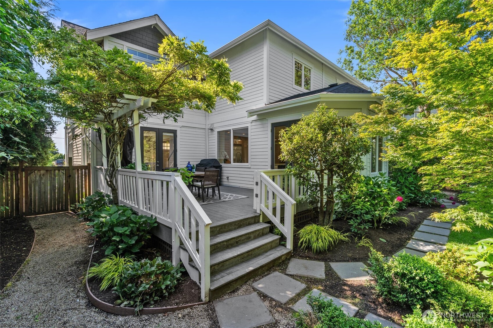 Charming fully-fenced backyard oasis featuring winding stepping stones, majestic mature trees, fragrant rose bushes, and an overall serene atmosphere perfect for relaxation and outdoor enjoyment.