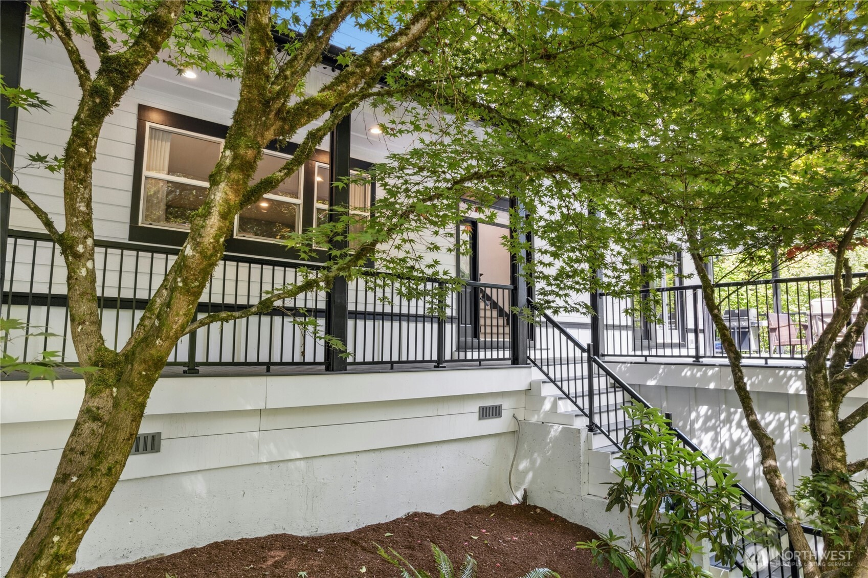 Inviting covered front porch framed by gorgeous Japanese maple trees.