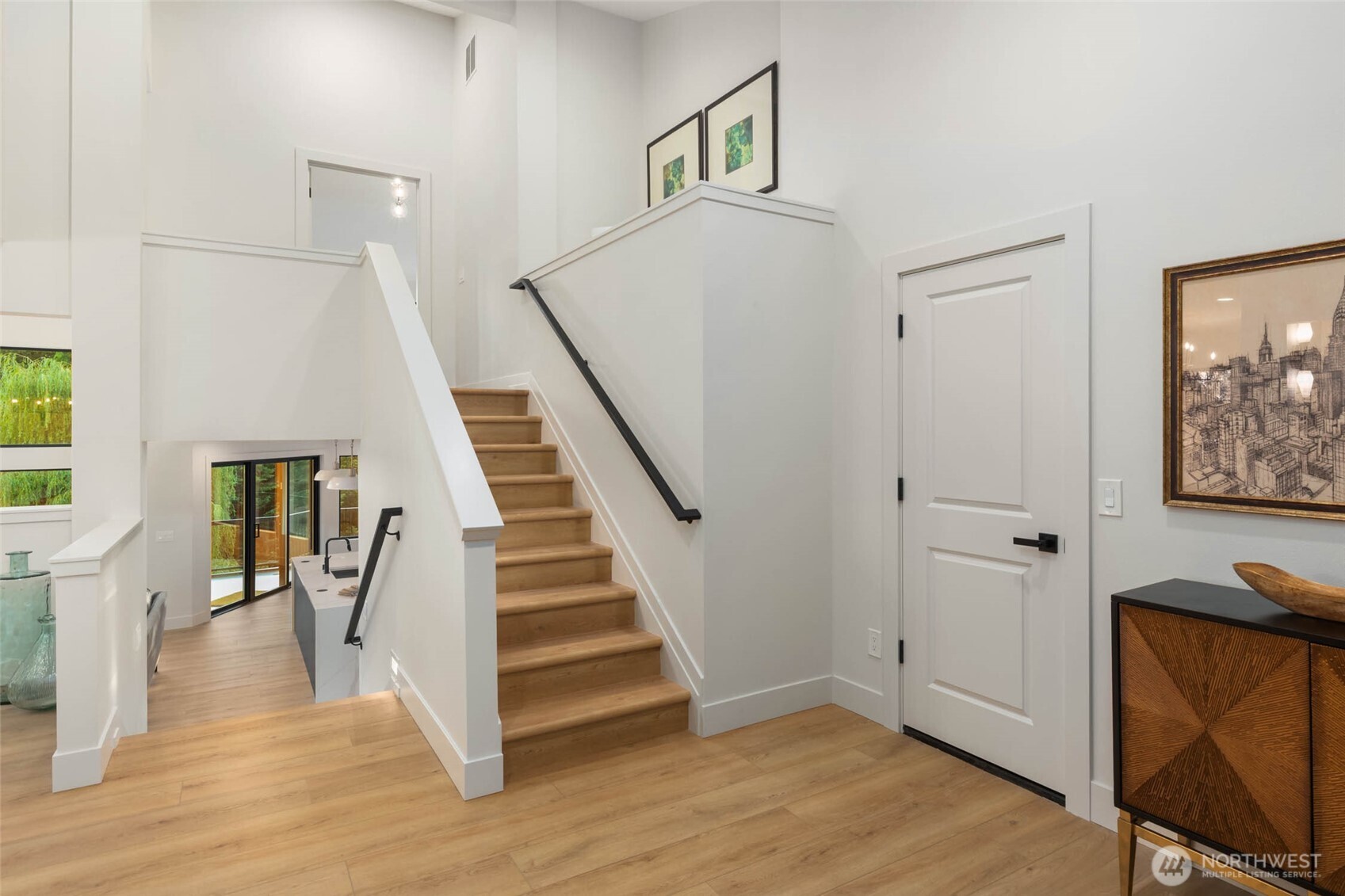 The entry foyer is the hub of the main level, providing access to the primary suite above, another bedroom & bath immediately to the left, the garage to the right and the dining, living, kitchen and family room straight ahead.