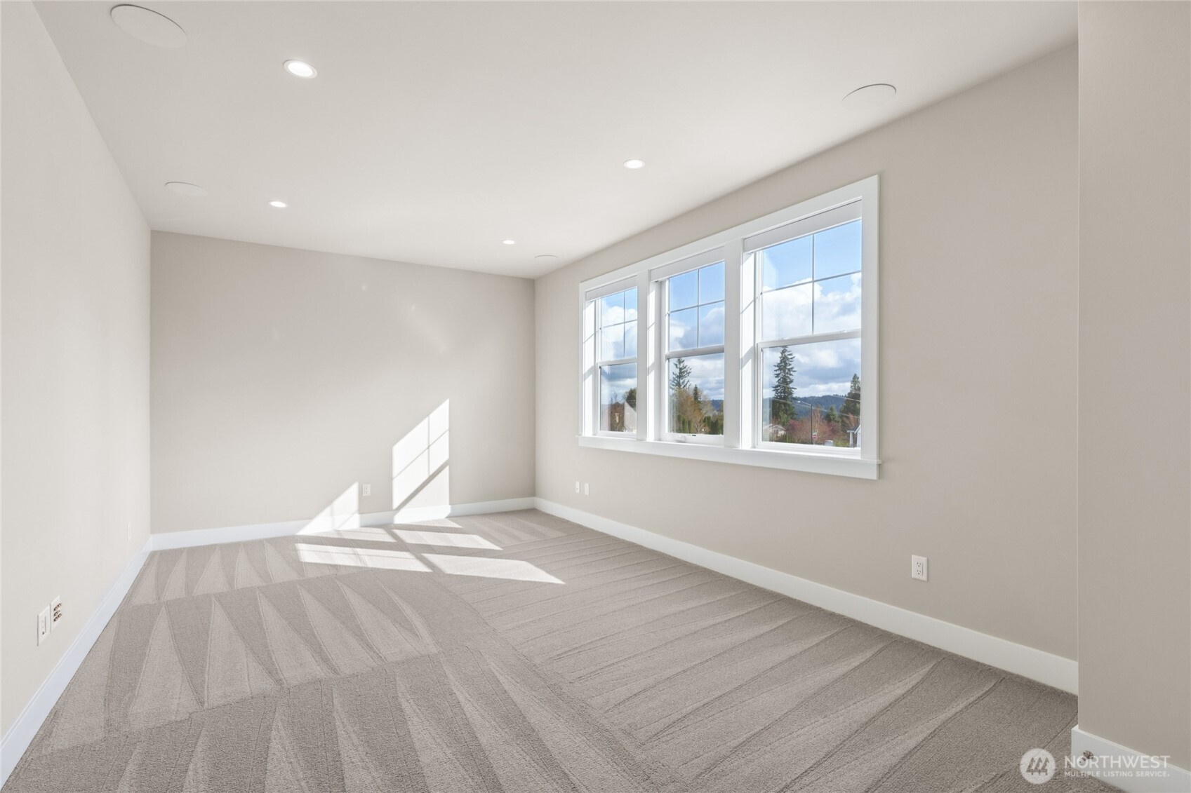Light-filled bedroom or flex space with plush carpet, recessed lighting, and large windows offering beautiful views of the surrounding landscape. A peaceful retreat with neutral tones and ample natural light.