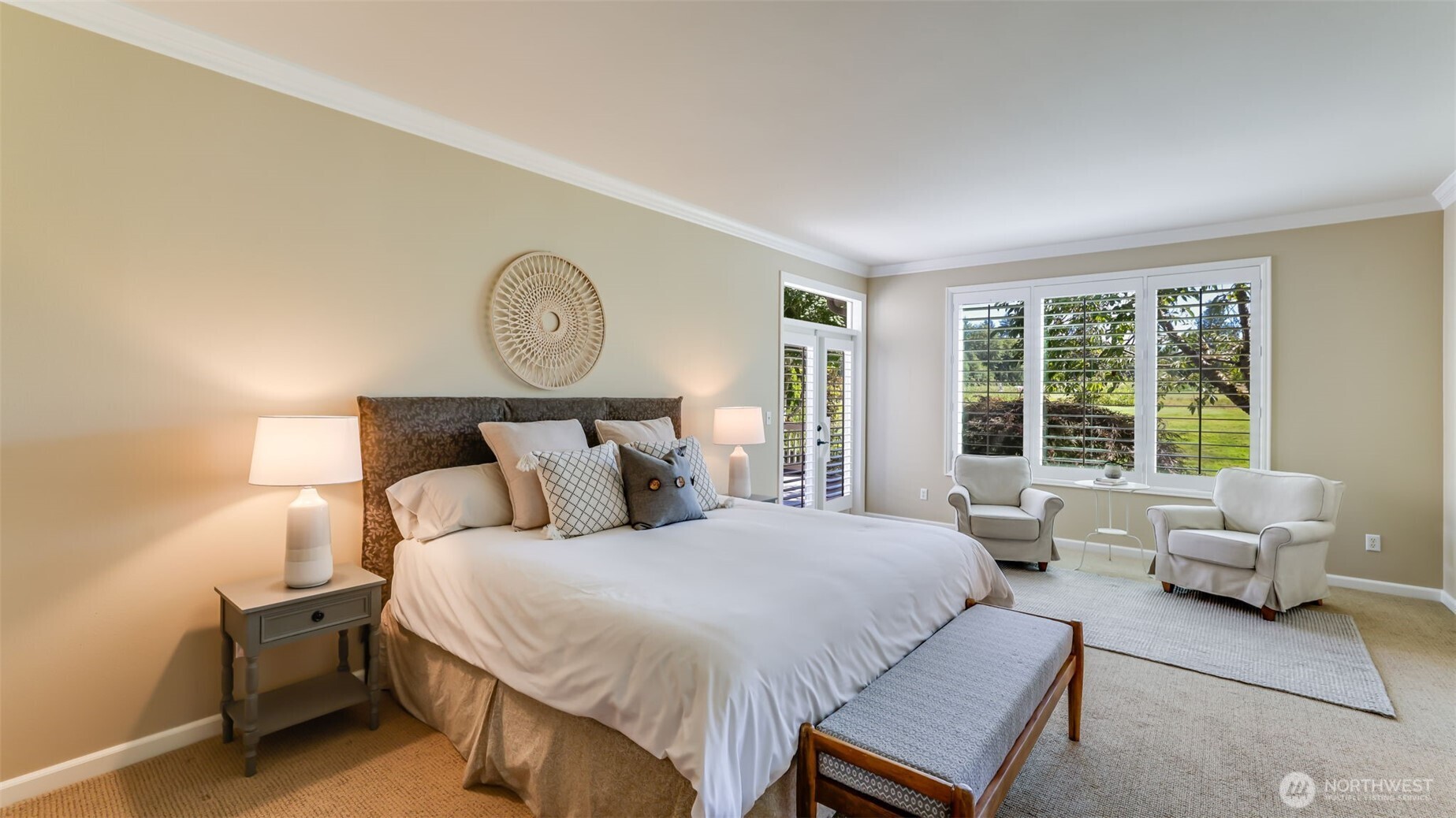 Expansive primary suite on the main floor with views of the golf course and French doors that lead out to the deck