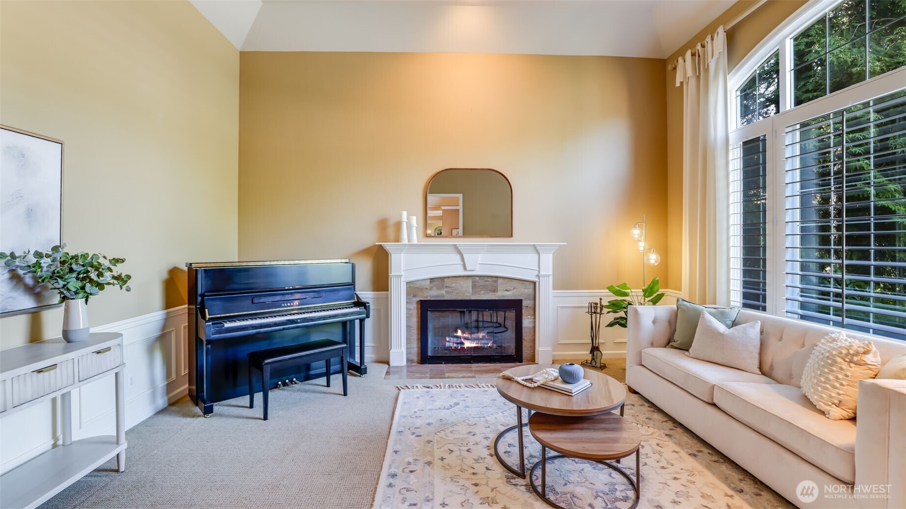 Formal living space off entry elegantly appointed with plantation shutters, marble-surround gas fireplace, wainscot paneling and coffered ceiling