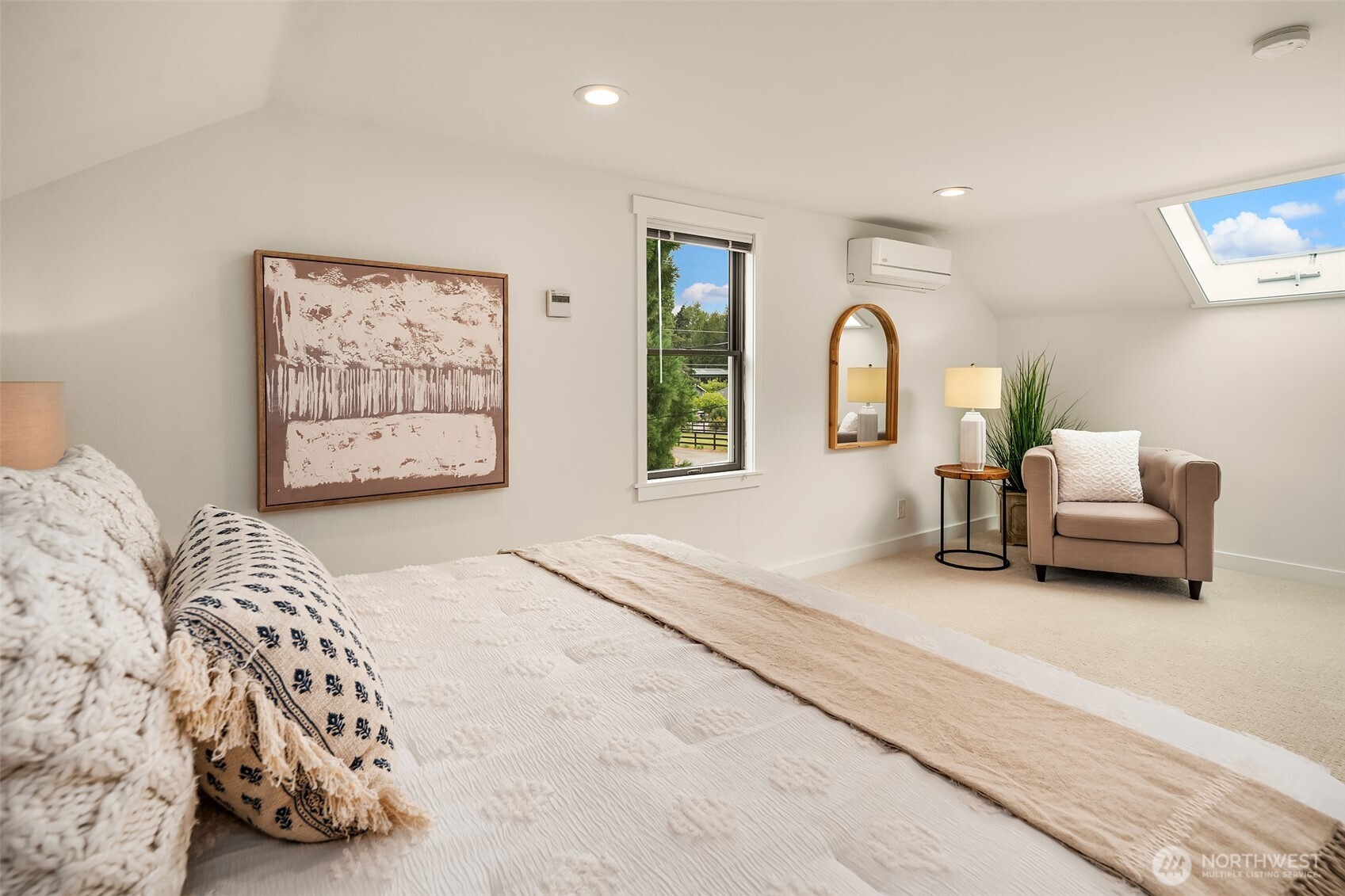 Upper floor primary bedroom with seating area, skylight and XL closet