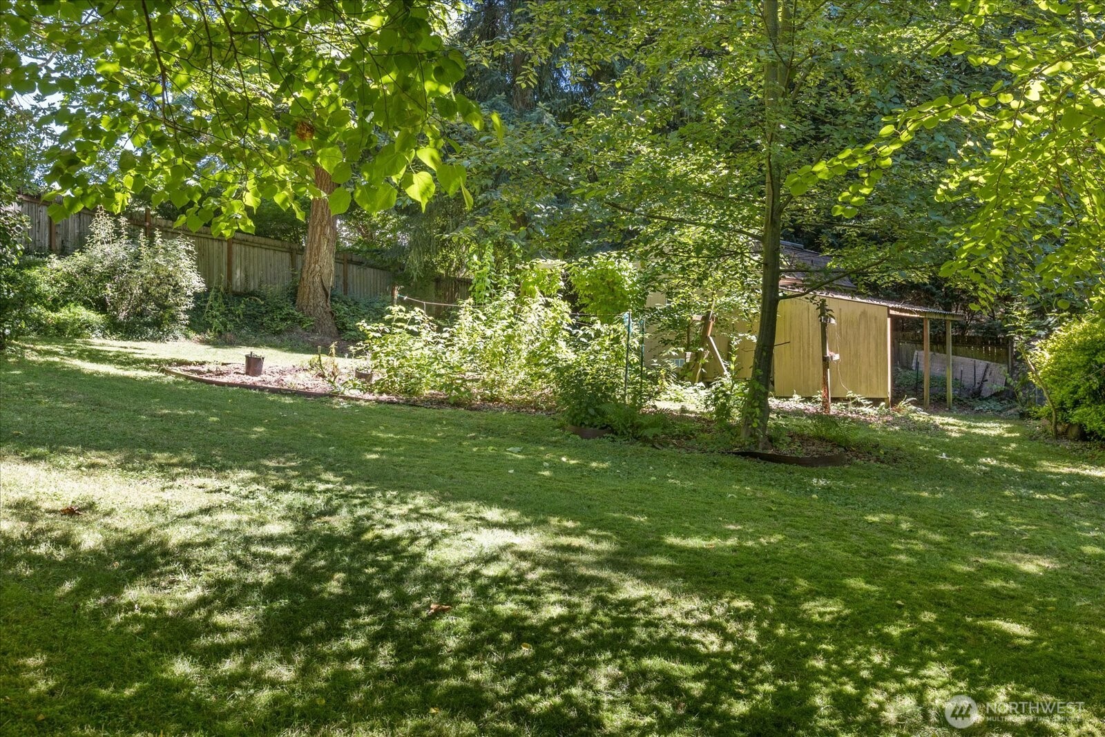 The spacious backyard features lush grassy areas and vibrant gardens, creating a peaceful and inviting outdoor retreat.
