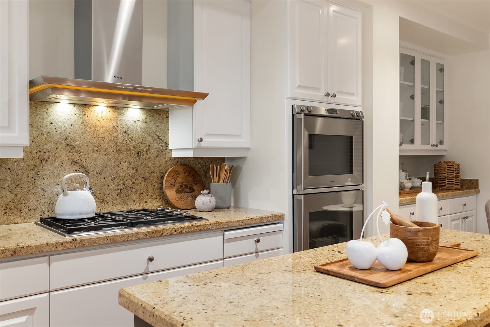 Warm granite counters and back-splash work beautifully with the warm floors and white wood cabinets.