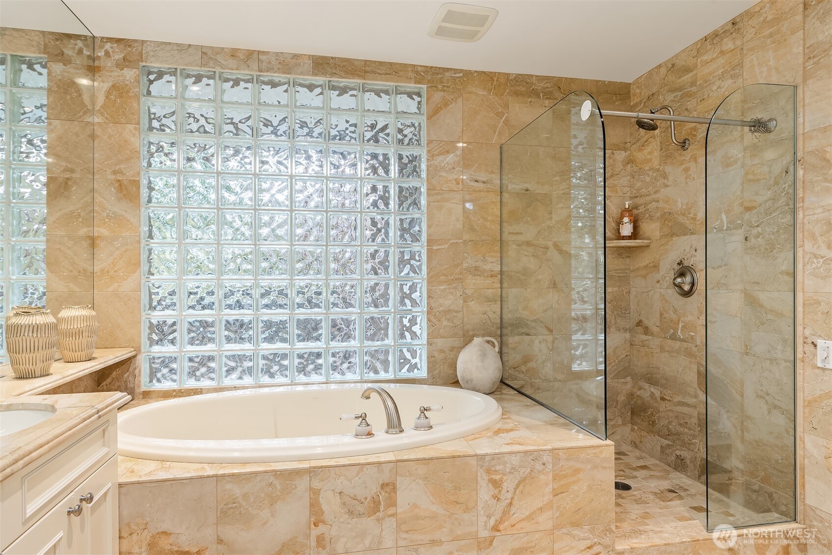 The elegant glass shower showcases the surround of beautiful, full tile walls and floors.