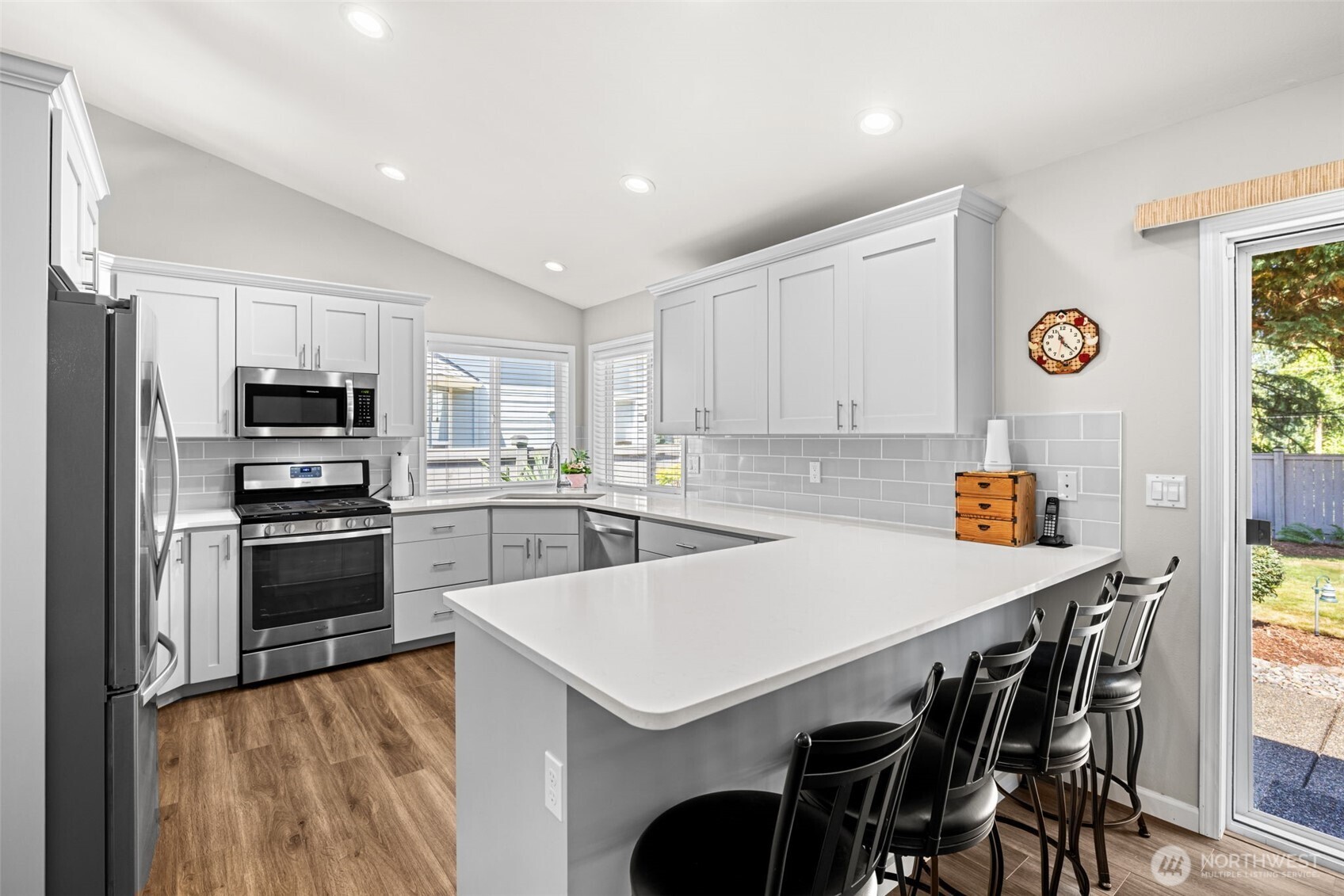Newly updated kitchen with soft closing white cabinetry, subway pattern deco tile backsplash, quartz countertops, stainless steel appliances, and walk in pantry space in laundry room.