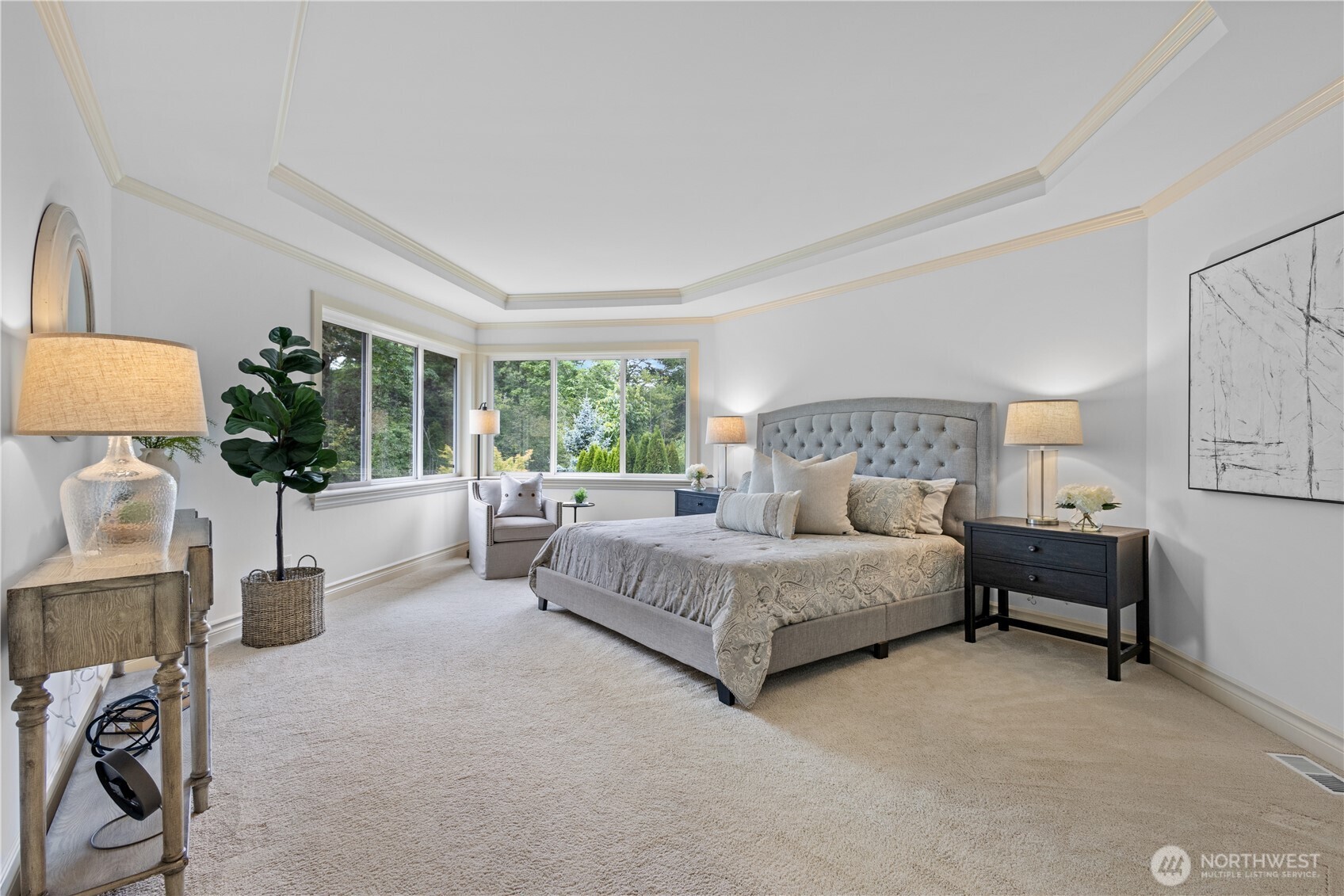 Serene primary suite with tray ceiling and peaceful greenbelt views.