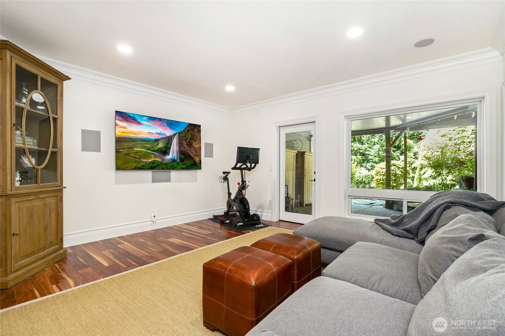 Versatile lower-level bonus room with large windows, custom millwork, built in surround sound and space for media, fitness, or relaxation—offering flexible living with direct outdoor access.