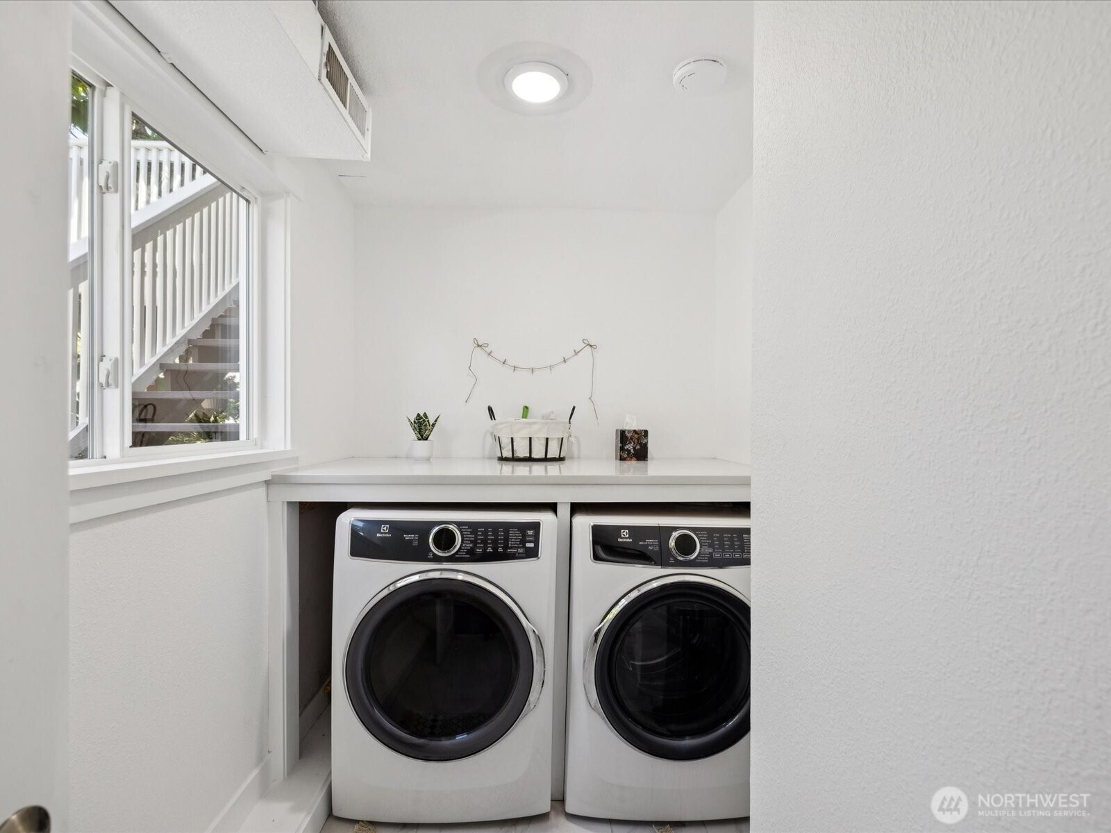 Gorgeous dedicated laundry room complete with folding shelf, Electrolux washer & dryer, room is full of natural light