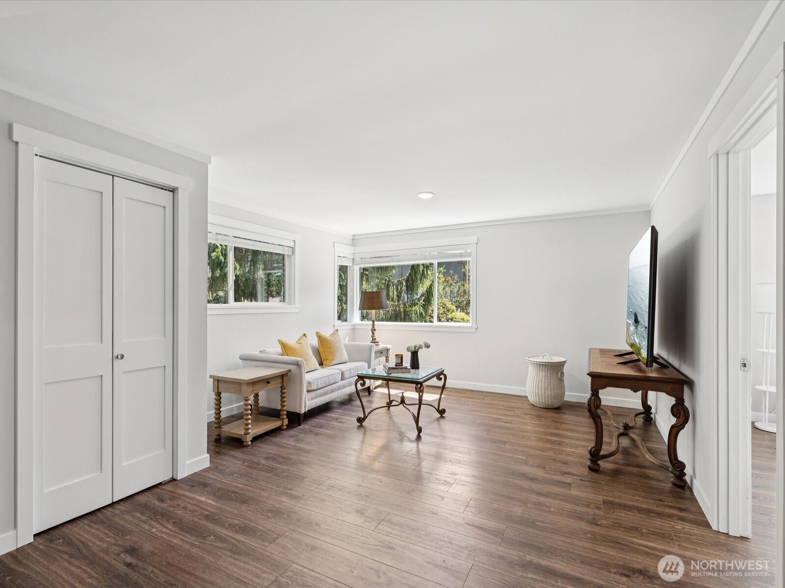 View of family room from just past the foyer, storage closet behind closed doors, bedroom #3 is just to the right in front of the television