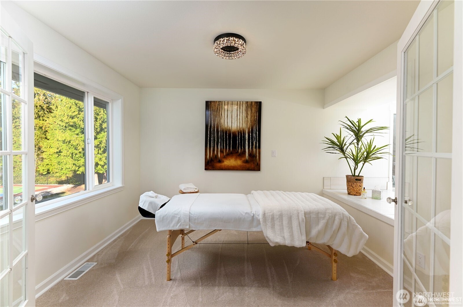 Master bedroom/primary suite offers an adjacent versatile room perfect for serene spa area, sitting or hobby room, nursery, or additional office space featuring french doors, luxurious carpet and custom lighting.