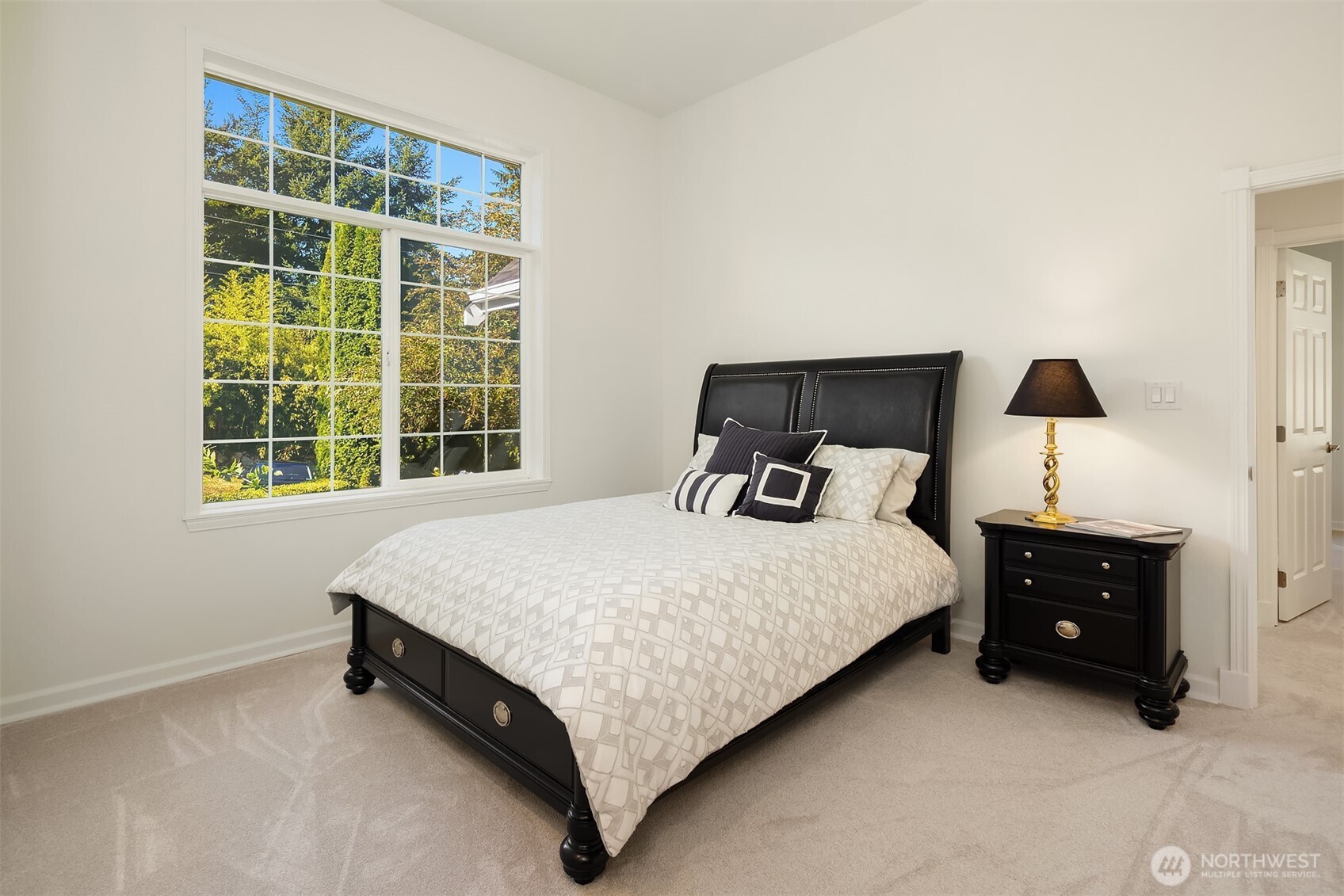 The third of four additional large oversized bedrooms on the main level boasts custom closet organizer, luxurious carpet, and expansive windows that flood the space with natural light and overlook park-like setting.