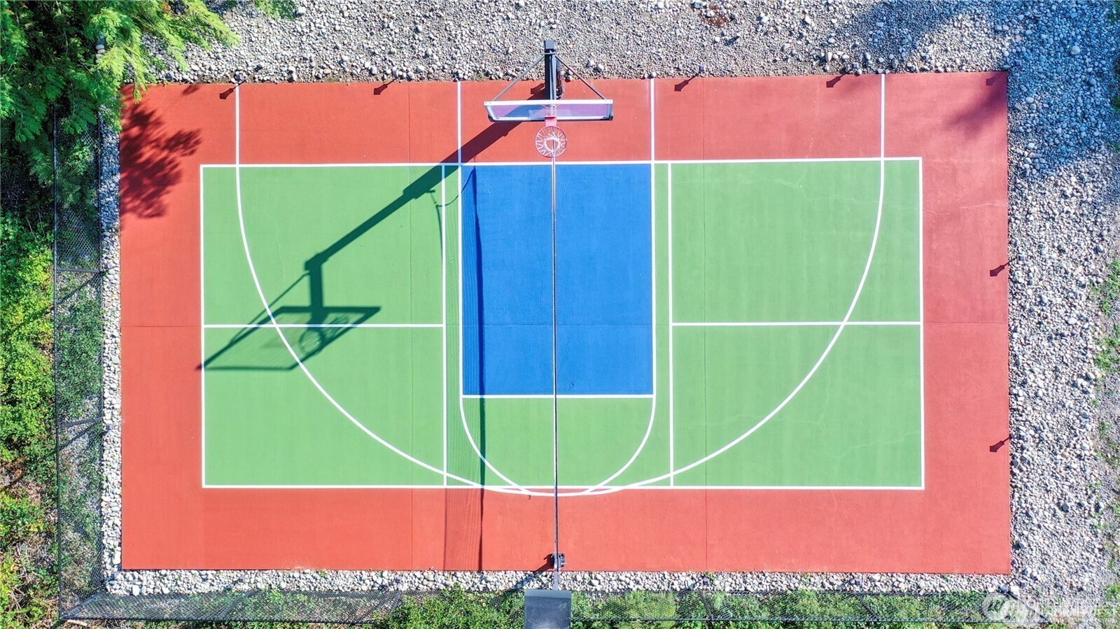 Aerial view of the well-maintained outdoor sports court, perfect for basketball, tennis, pickleball, or a variety of recreational activities - offering plenty of space for fun and fitness right at home.
