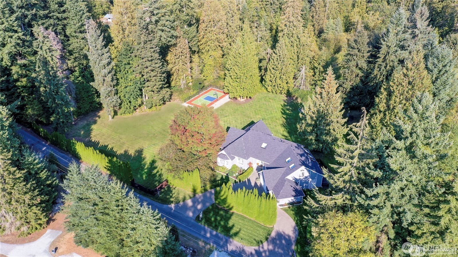 Aerial view showcasing the completely remodeled estate, its surrounding 5-acre equestrian property, sports court, and peaceful park-like setting.