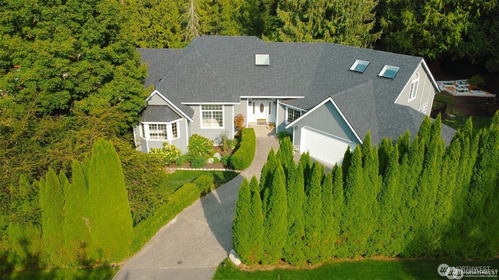 Aerial view showcasing the picturesque estate - featuring the new roof, new exterior paint, beautiful surrounding landscape and private setting.