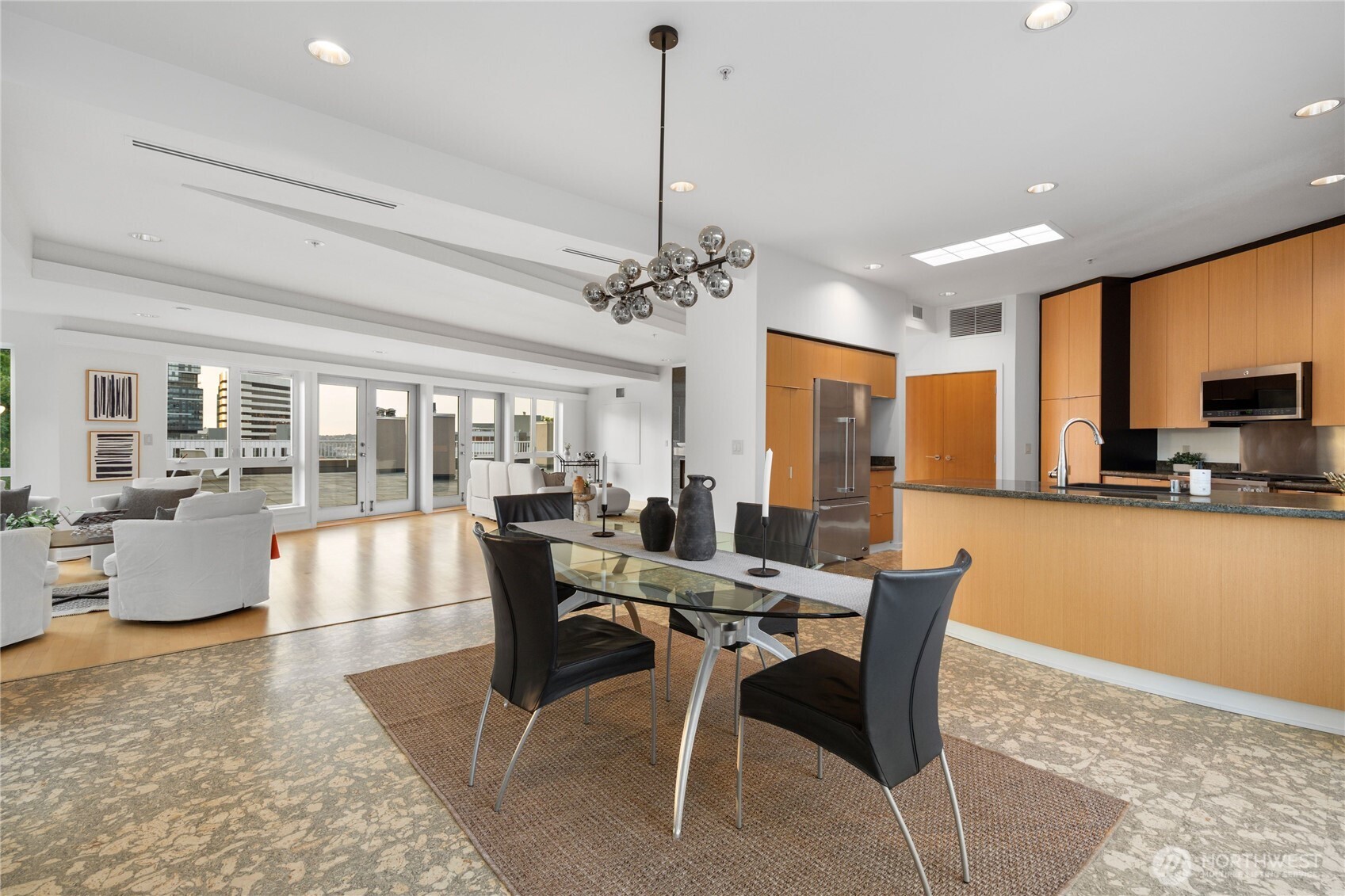 An oversized dining area transitions effortlessly to the kitchen set upon sustainable cork flooring.