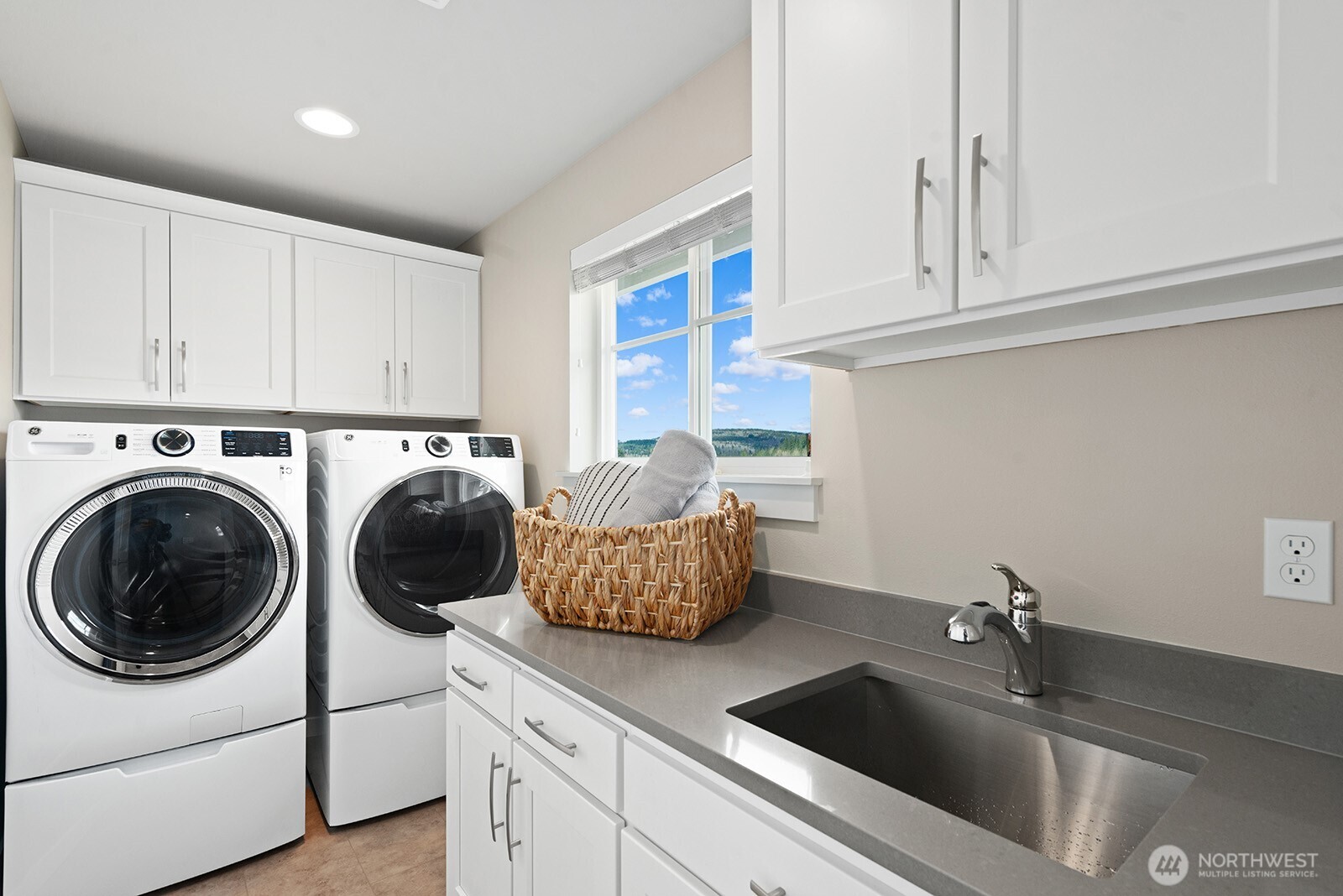 Laundry room conveniently located outside of the primary bedroom with extra storage, folding table and sink.