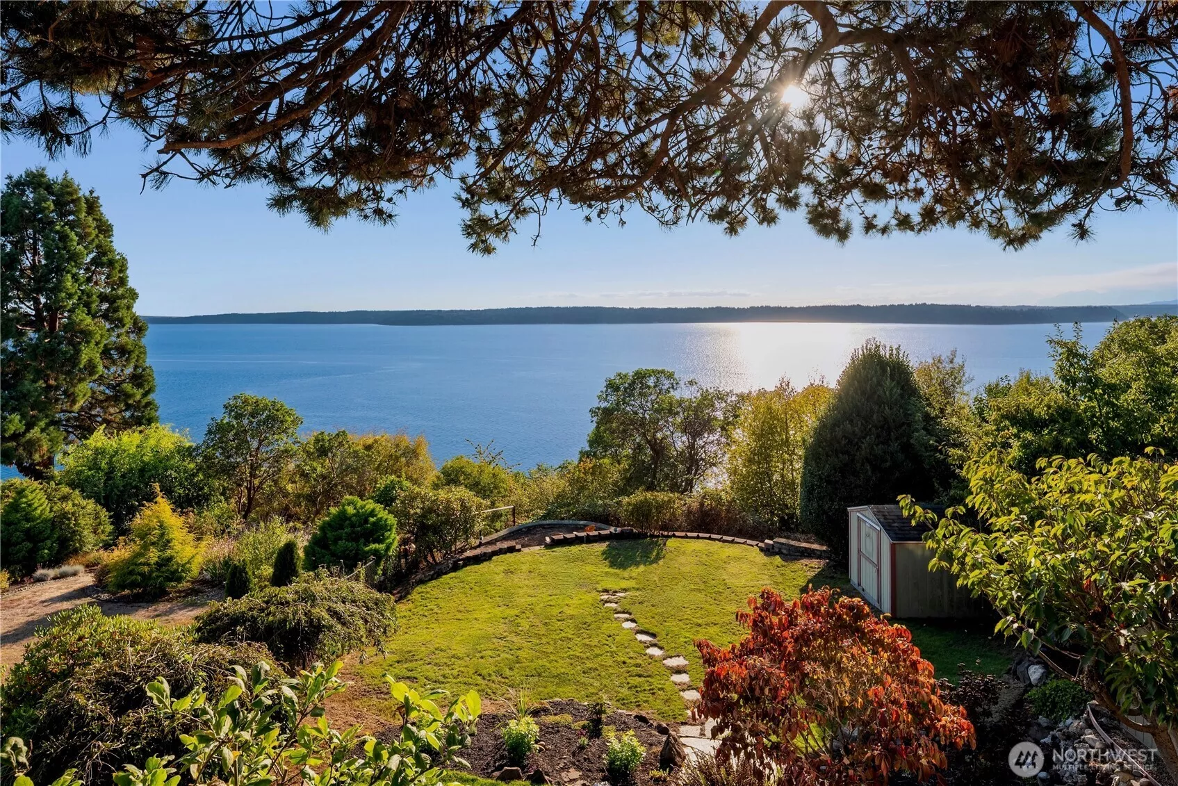 Dappled sunlight filters through evergreens onto this idyllic deck, where tranquil water views create the perfect backdrop for al fresco dining.