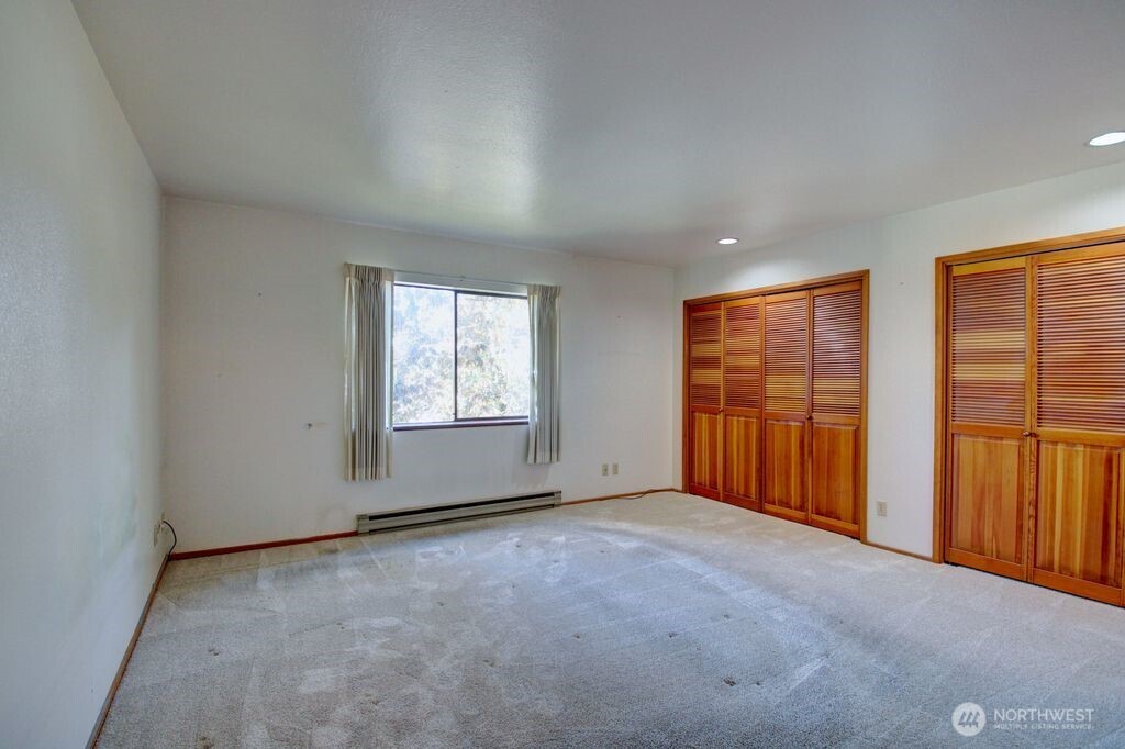 View of primary bedroom looking towards hallway and door to bathroom.