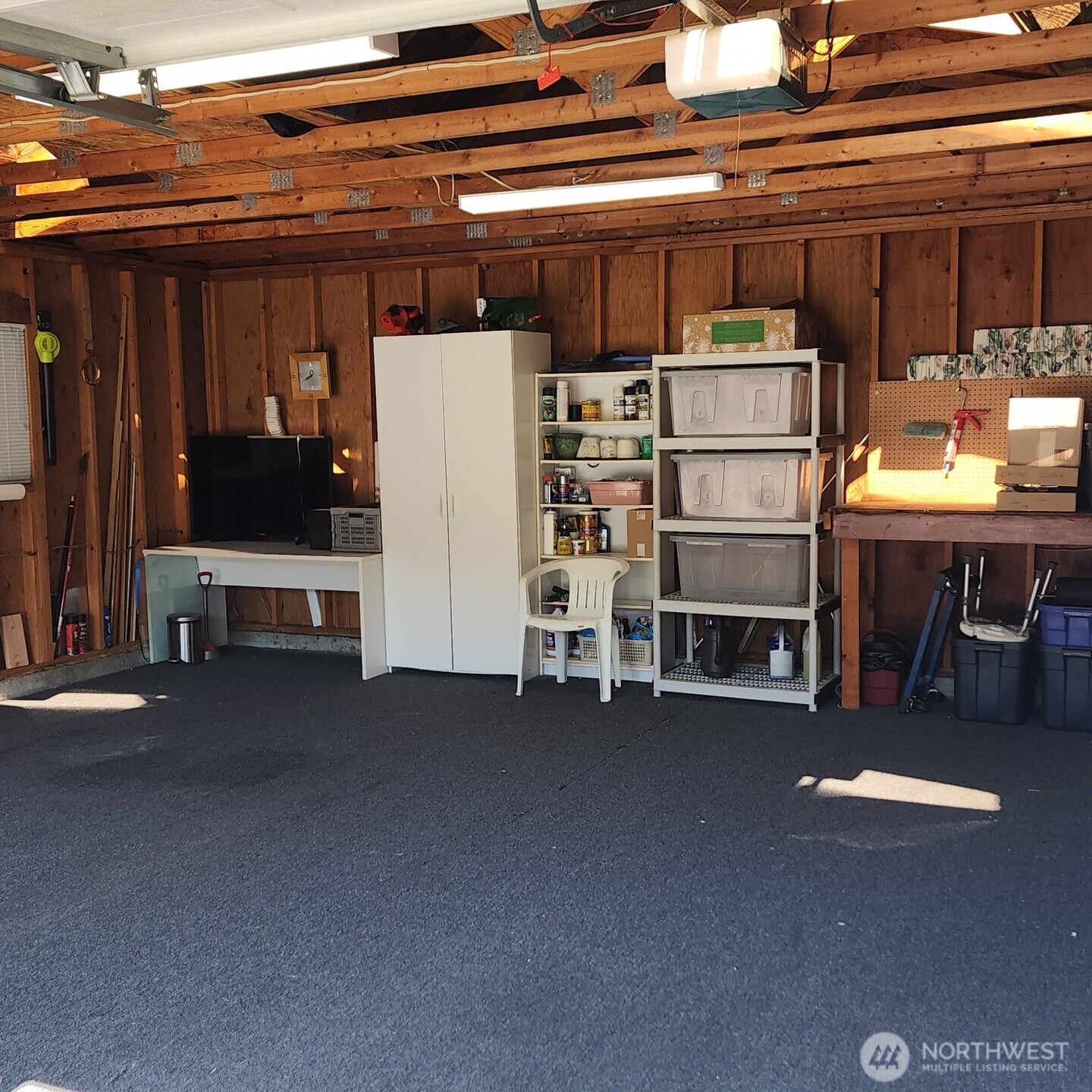 Garage is roomy with additional shelving and storage.