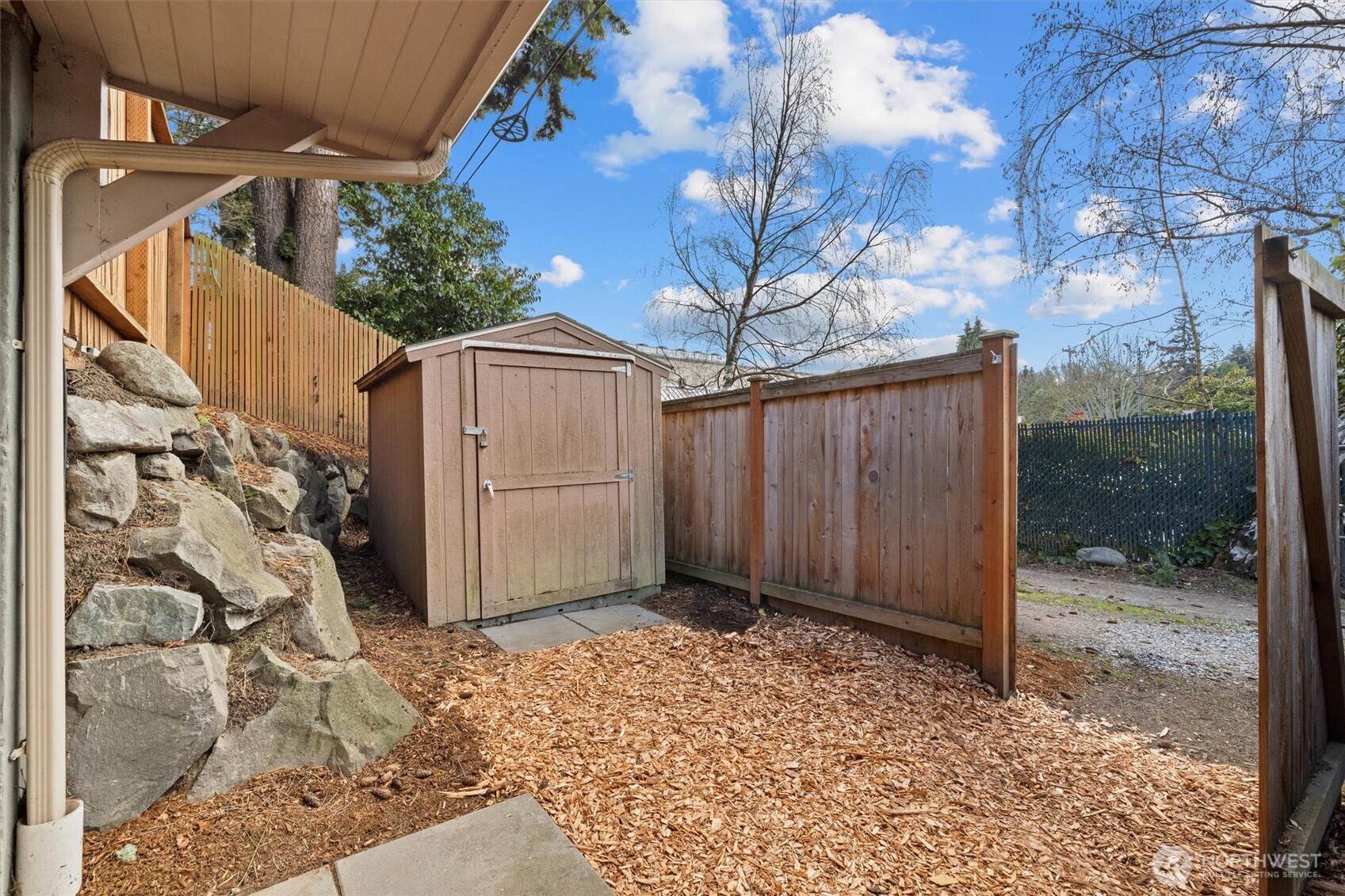Fenced area at ground level off the media room. Here you see the gate opened, and the storage shed. Fencing is throughout the back and on this side of the property.