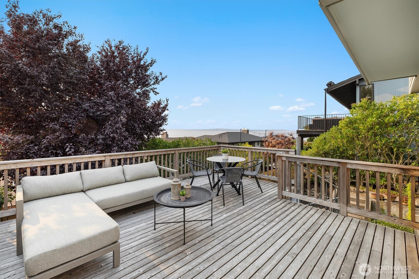 The expansive cedar deck extends the living space outdoors, offering room for both lounging and dining. Surrounded by mature landscaping, it provides privacy while opening to views of Shilshole Bay.