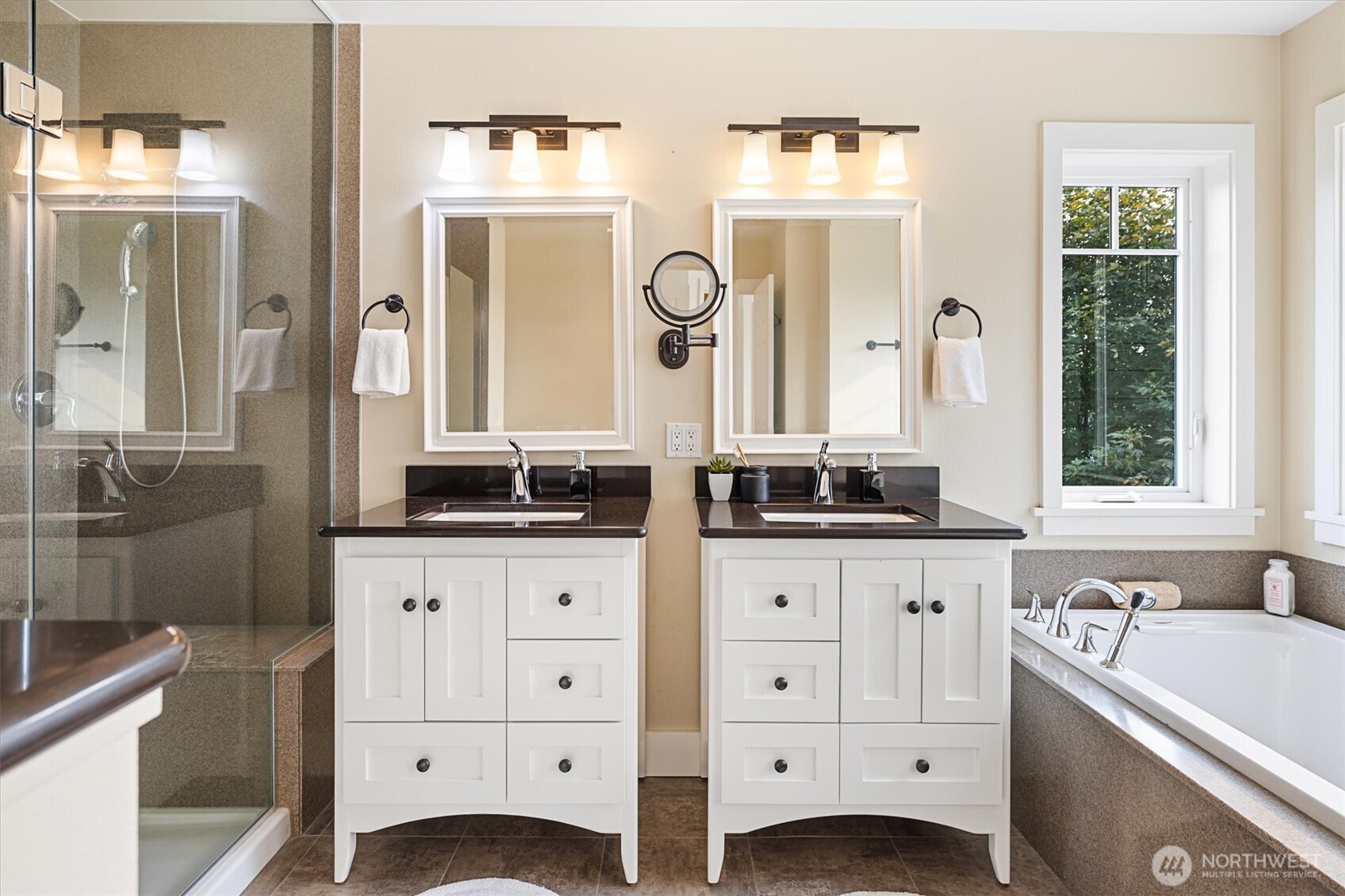 The spa-inspired primary bath features dual vanities, a soaking tub framed by windows, and a walk-in glass shower. Thoughtful finishes and natural light create a serene retreat for daily routines or unwinding at the end of the day.