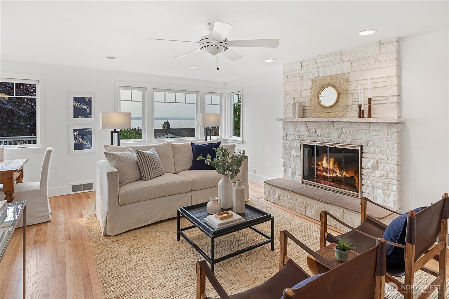 The living room offers a warm and inviting setting, anchored by a gas fireplace and accented with freshly painted walls and refinished solid oak hardwood floors. Neutral tones and an open layout create a seamless flow into the dining area.