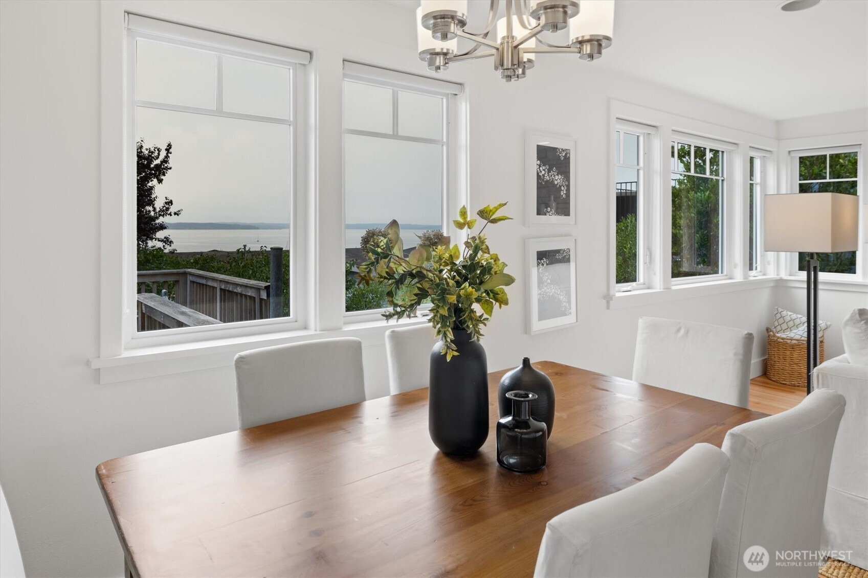 From this vantage, the dining room showcases its scenic outlook with water views framed by oversized windows. Natural light enhances the clean, modern design, while the open connection to the living room makes the space equally suited for relaxed gatherings or elegant dinners.