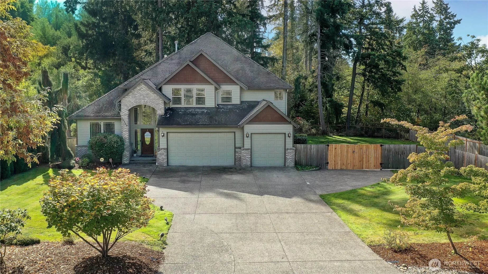 This beautiful two-story home in South Hill, Puyallup, sits on a spacious, well-manicured lot surrounded by mature trees, offering privacy and a serene natural backdrop. The exterior features a blend of brick and siding with charming architectural details, including a covered entryway and large front-facing windows. The home boasts a three-car garage and a wide driveway, perfect for additional parking and easy access. A tall wooden gate on the side leads to a fenced backyard, ideal for outdoor entertaining or secure RV/boat storage.