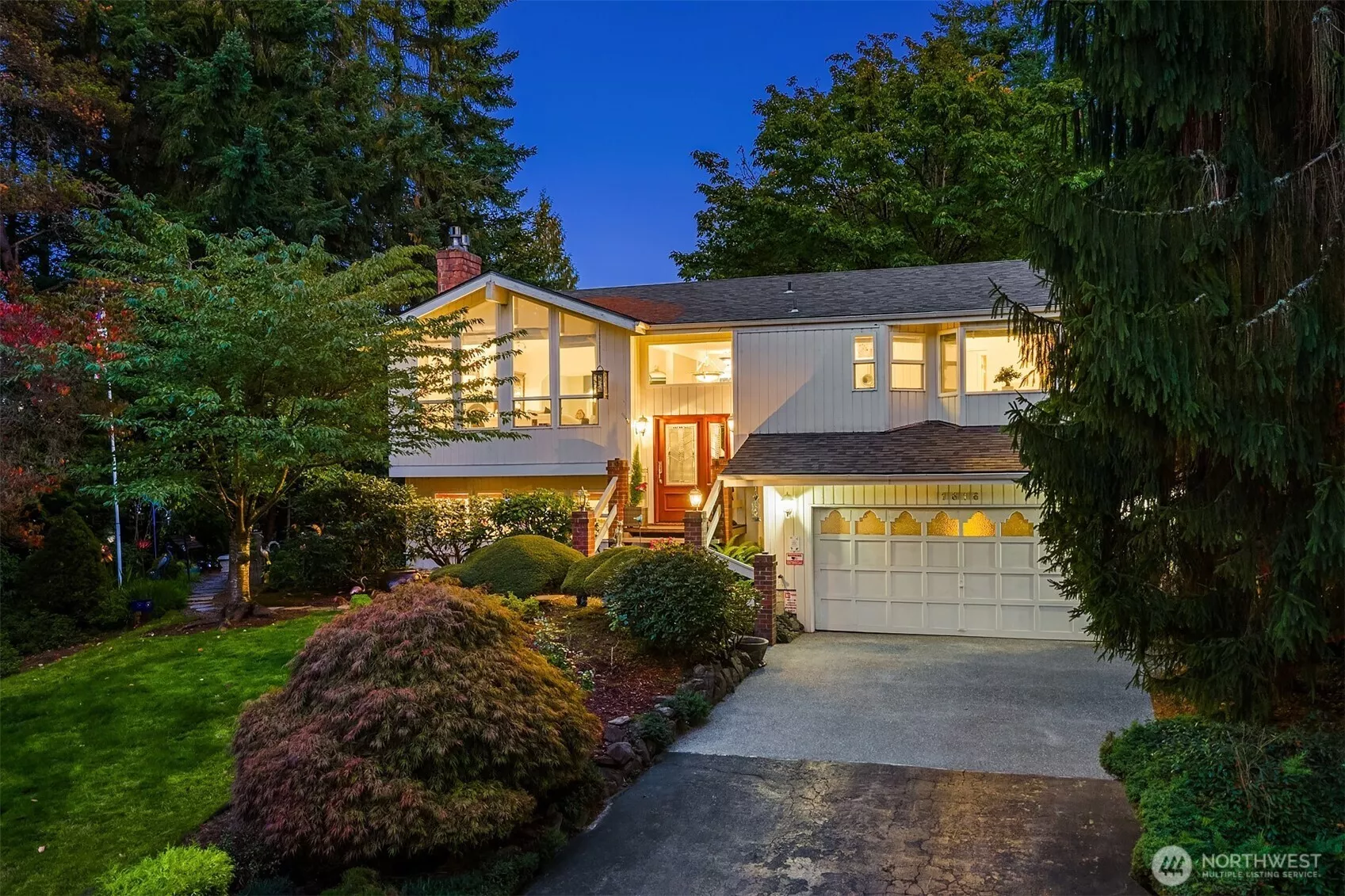 Nestled in a lush, park-like setting, this beautifully maintained home shines with warm evening glow and timeless curb appeal. Expansive picture windows flood the interior with natural light, while vaulted ceilings and a striking mid-century flair add a sense of openness and style. Mature landscaping frames the entry, creating a private oasis just minutes from town conveniences. Enjoy the inviting front porch, spacious driveway, and beautifully lit architectural lines that highlight the home’s welcoming character. Ideal for those who appreciate serenity, space, and thoughtful design in a prime location! ????
