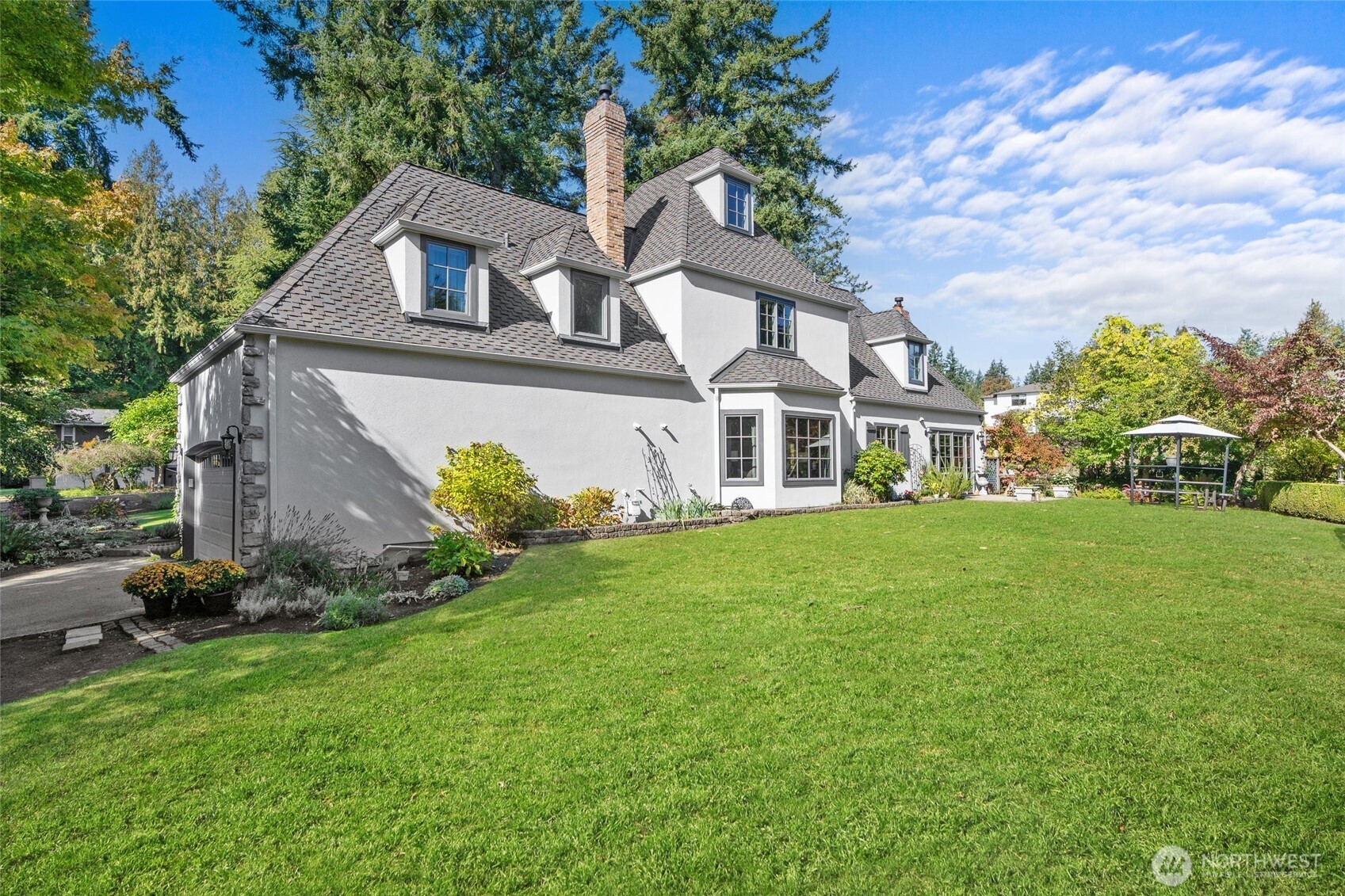 Mature garden beds and fenced area on side of house for waste bins.