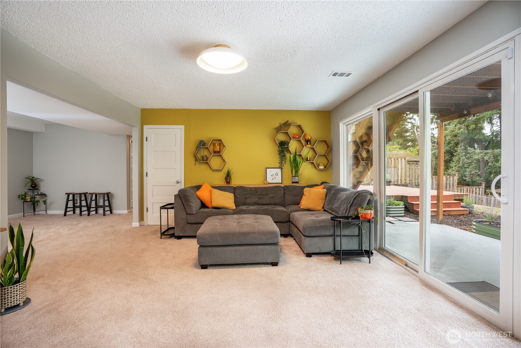 Extra storage is tucked under the stairs & the yard level patio & wood deck is seen beyond…