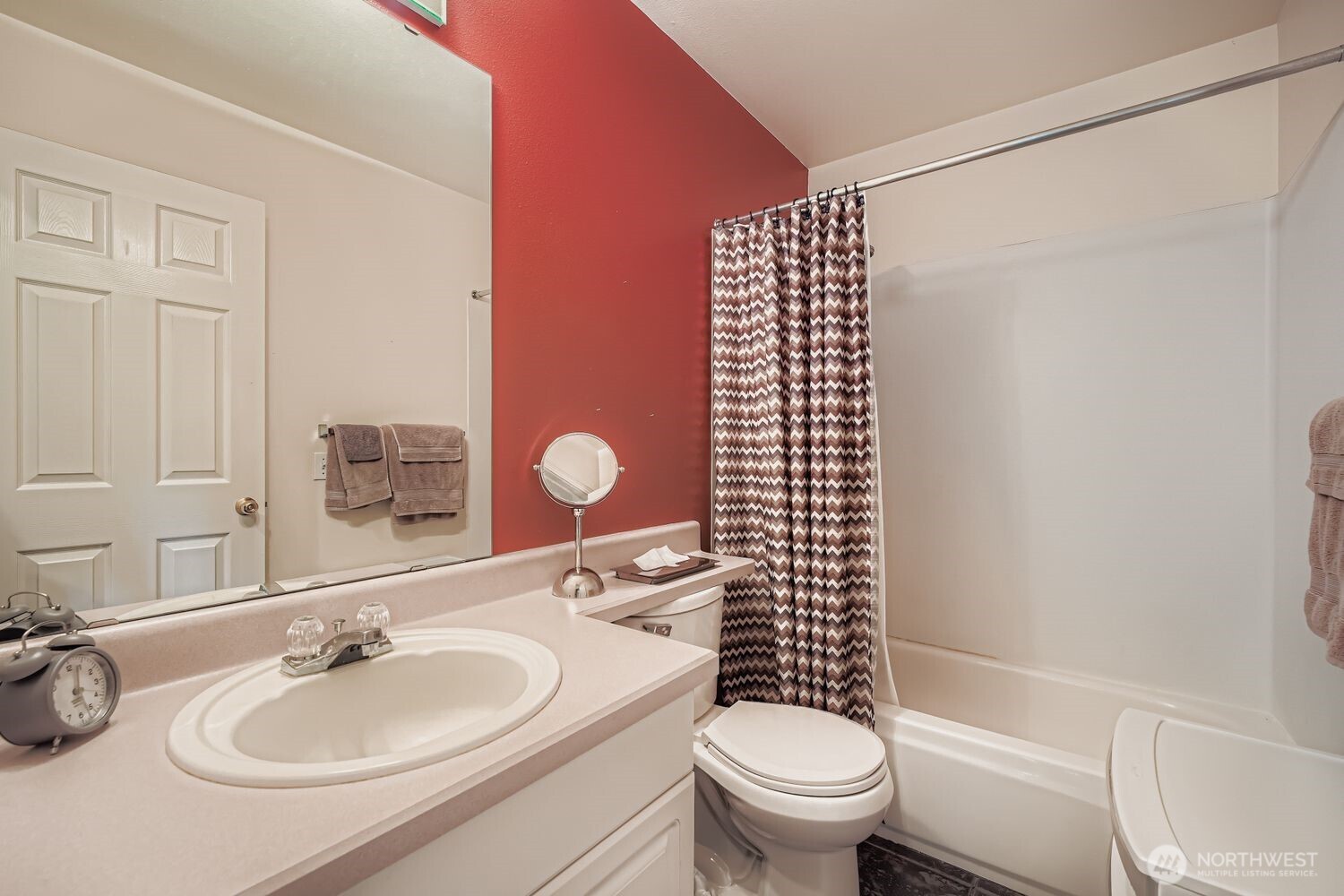 This dedicated laundry space offers convenience and efficiency with a top-loading washer and front-loading dryer that stay with the home. Overhead cabinetry provides ample storage, while tile flooring and contrasting wall tones add visual interest. A practical layout and clean design make everyday chores a breeze.