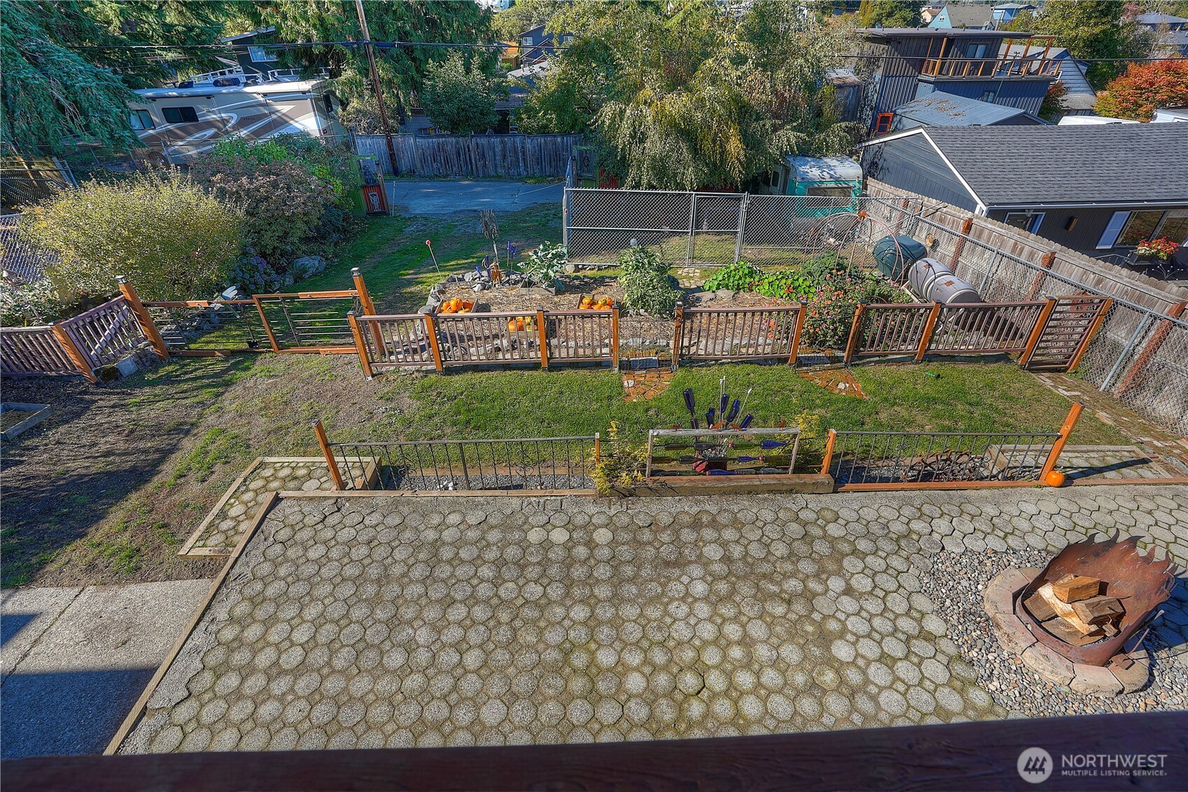 Looking down in to your yard. HUGE patio- this home is an entertainer's dream. Fun firepit is just one of the quirky pieces you will find in your yard. Most yard art stays. The double gate was made out of jail cell doors- so much personality. Patio, grass area, raised beds, then the chicken condo (gated area with the chicken trailer and 4 chickens.) Fresh eggs, fresh herbs, fresh veggies, and fresh fruit. Urban homesteading at its best.