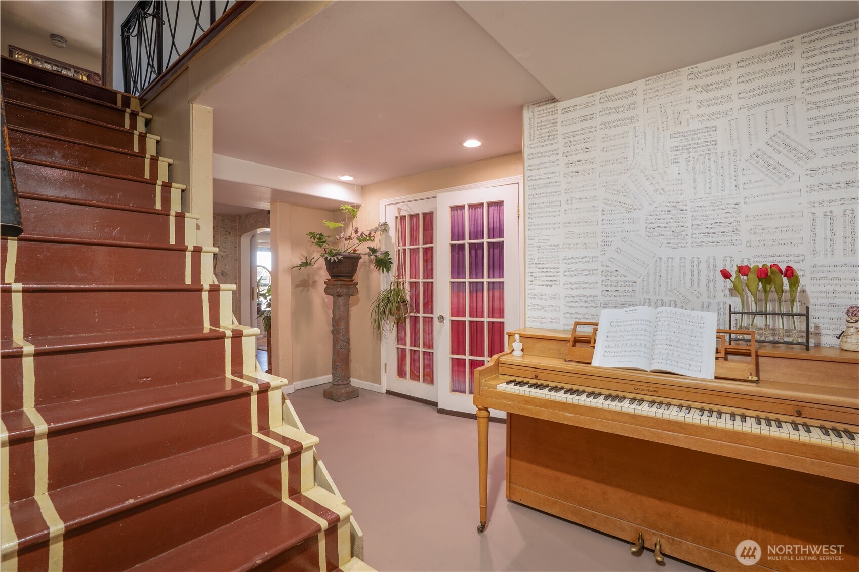 Heading downstairs, we have a large landing area, currently used as a music room, but you could pop a loveseat, desk, whatever, down here. French doors lead to a flex room, adding to more possibilities.