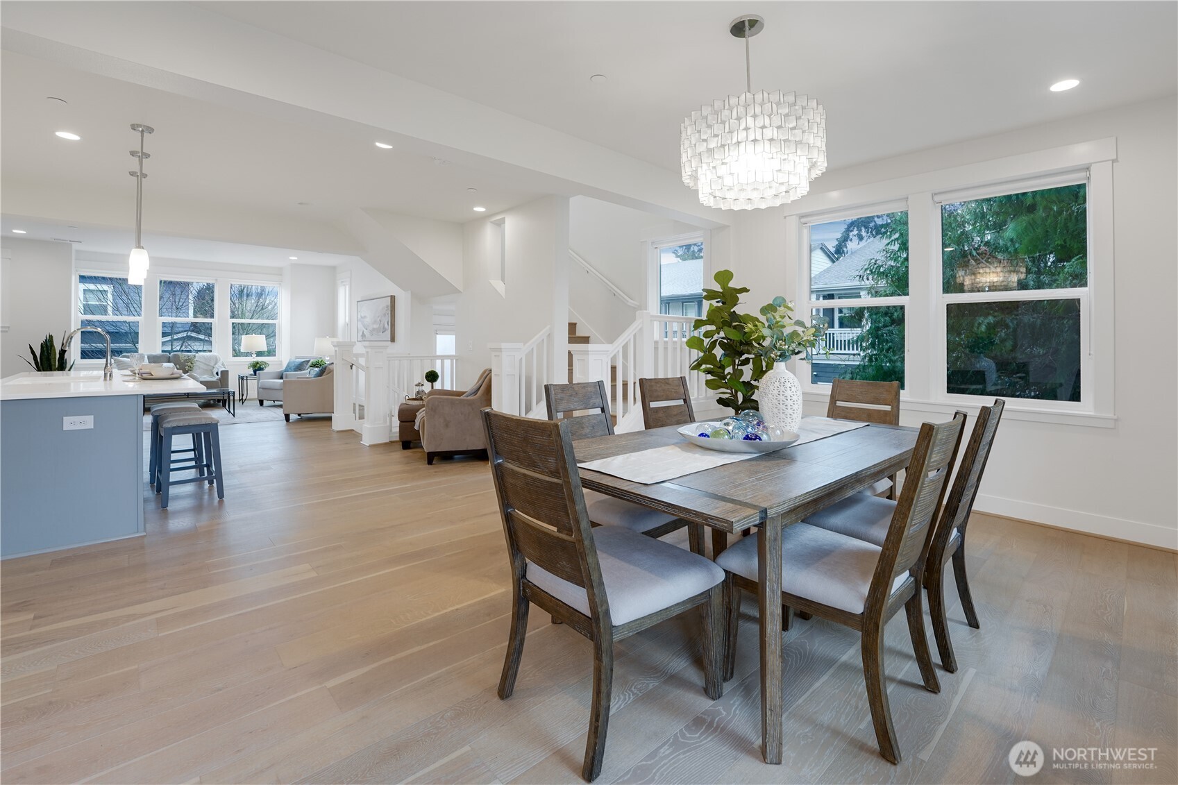 The dining space is filled with natural light, offering serene views over the deck and the green field beyond. All windows throughout the home feature custom blinds, adding both style and privacy to this inviting setting.