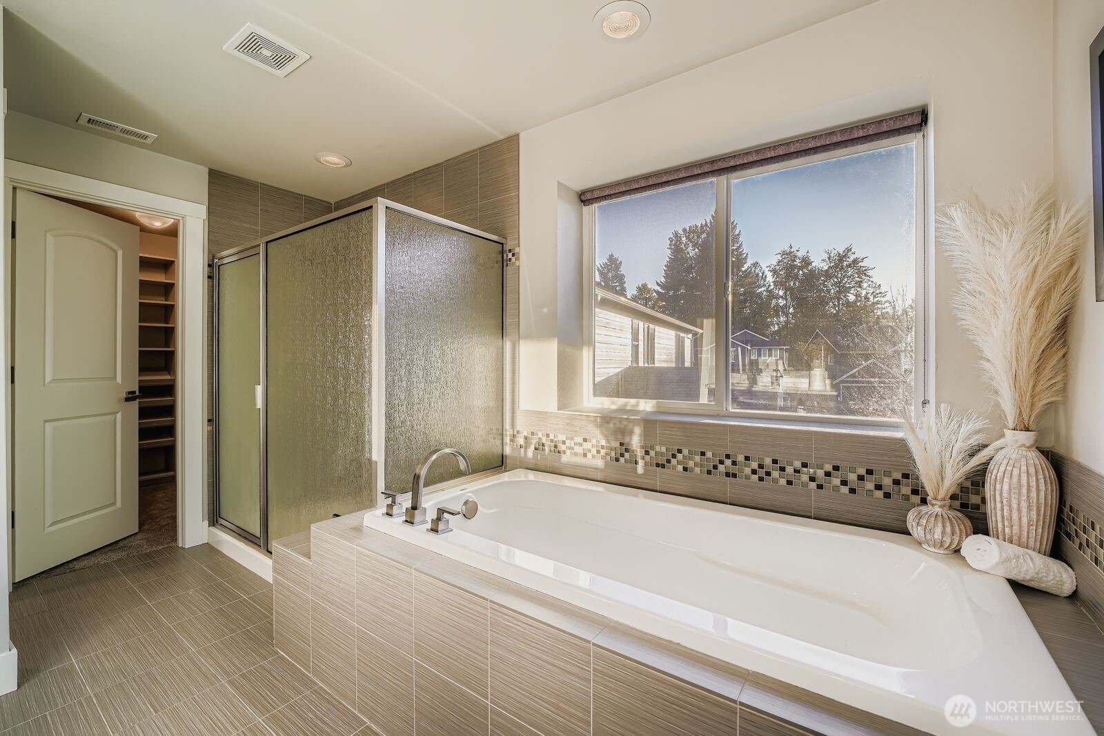 En suite bath with dual sinks, soaking tub, and walk-in shower