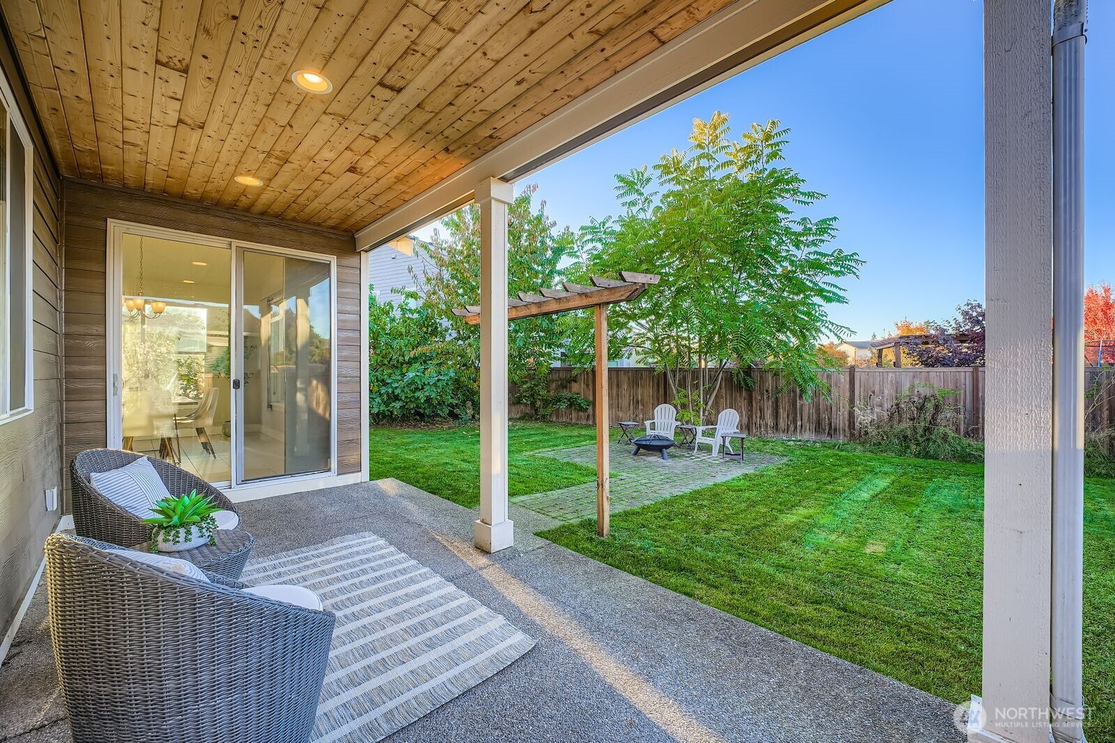 Covered porch with brick pavers leading to outdoor fire bowl.