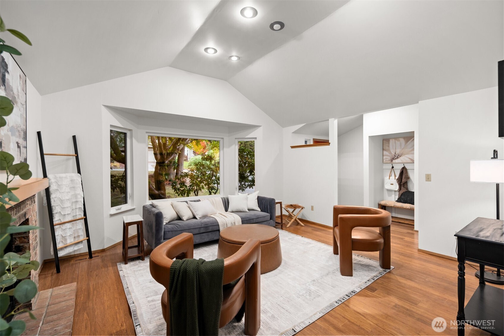 Inviting living room looking out onto picturesque front yard with professionally maintained trees.