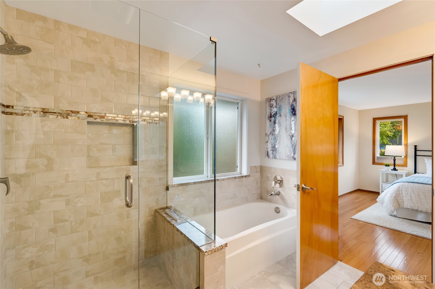 A luxurious spa-inspired layout with a soaking tub, glass-enclosed shower, and elegant finishes throughout. The skylight adds a soft, natural glow to the space.