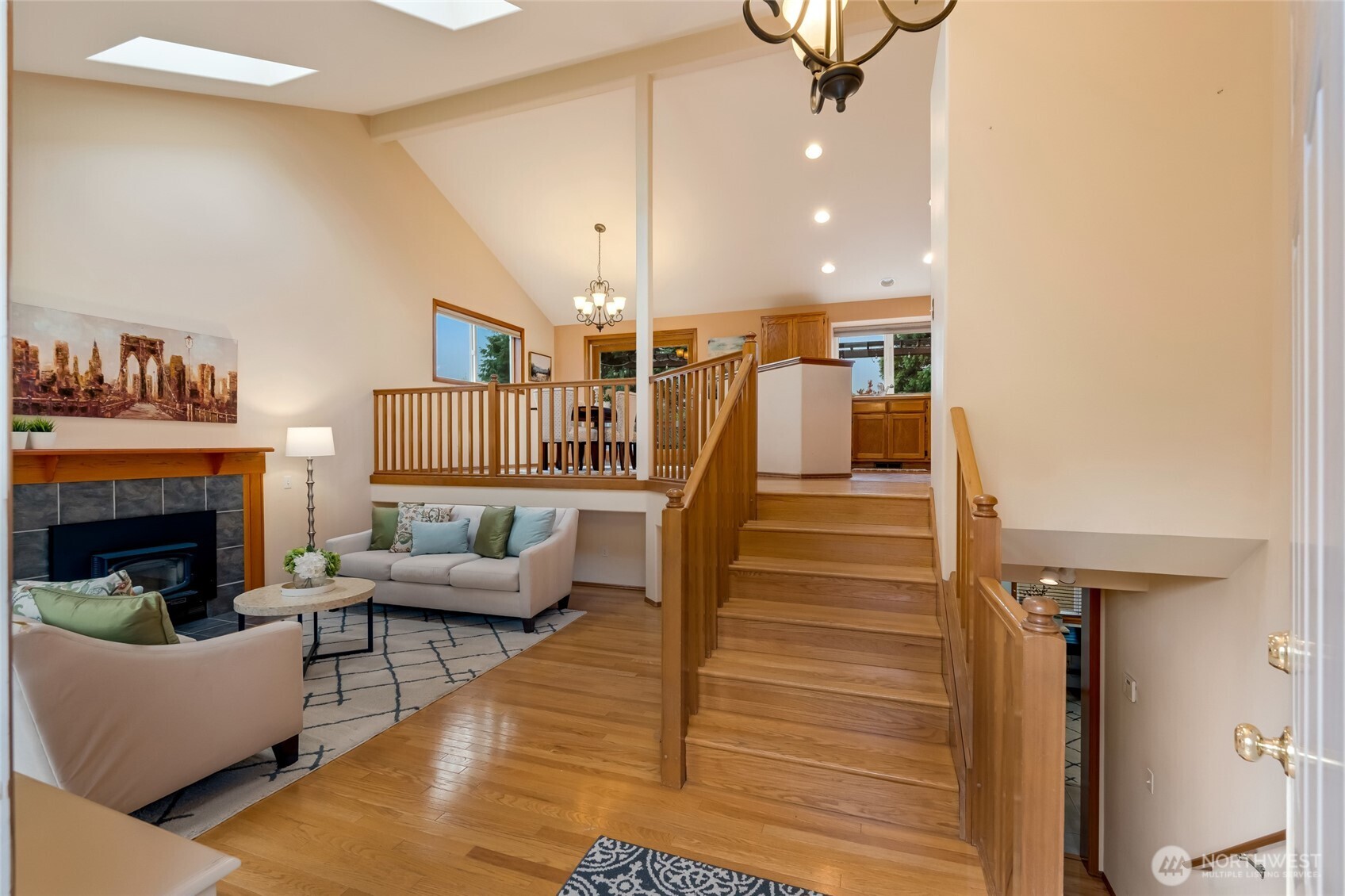 The entryway opens to a warm and welcoming floor plan with hardwood floors and vaulted ceilings. The multi-level layout offers a natural flow between the living room, dining area, and kitchen.