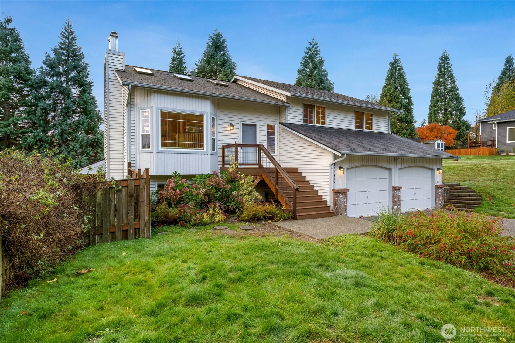 Thoughtfully updated exterior with a Trex deck and railing, brick accents, and vibrant plantings that complement the home’s light siding.