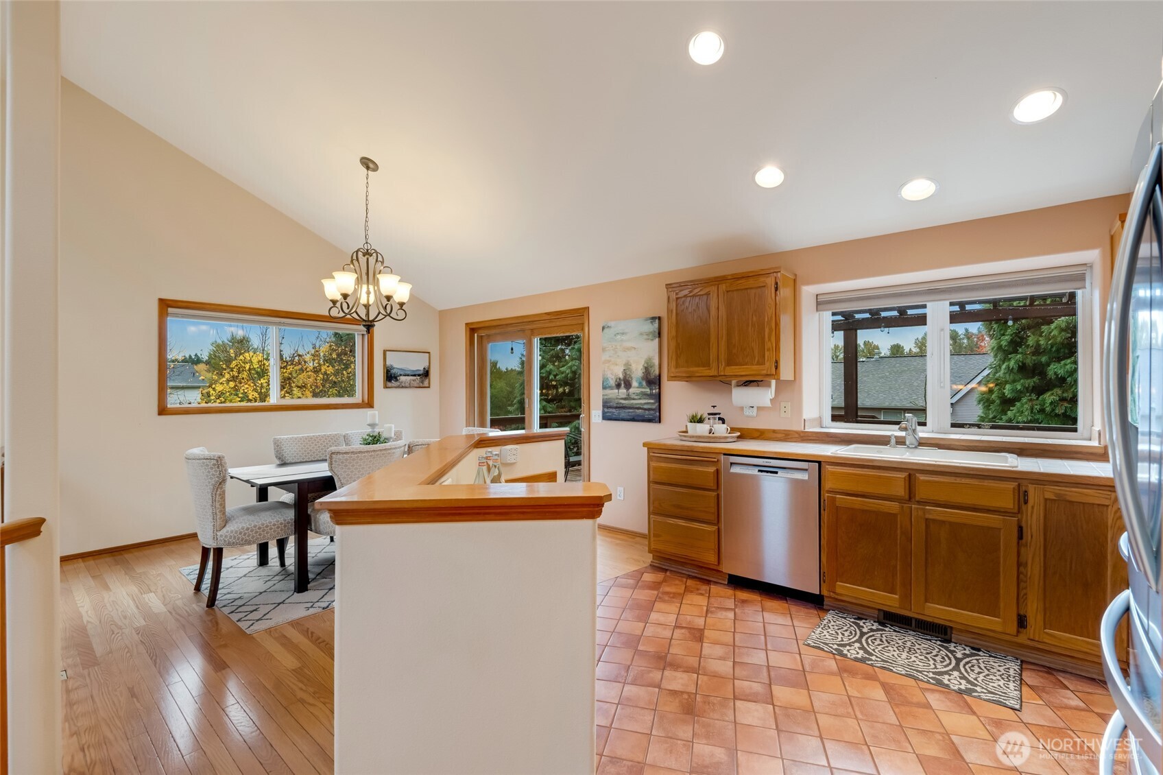 The kitchen flows seamlessly into the dining area, where large windows and sliding glass doors frame views of mature trees and the huge backyard. Perfect for casual meals or gatherings.