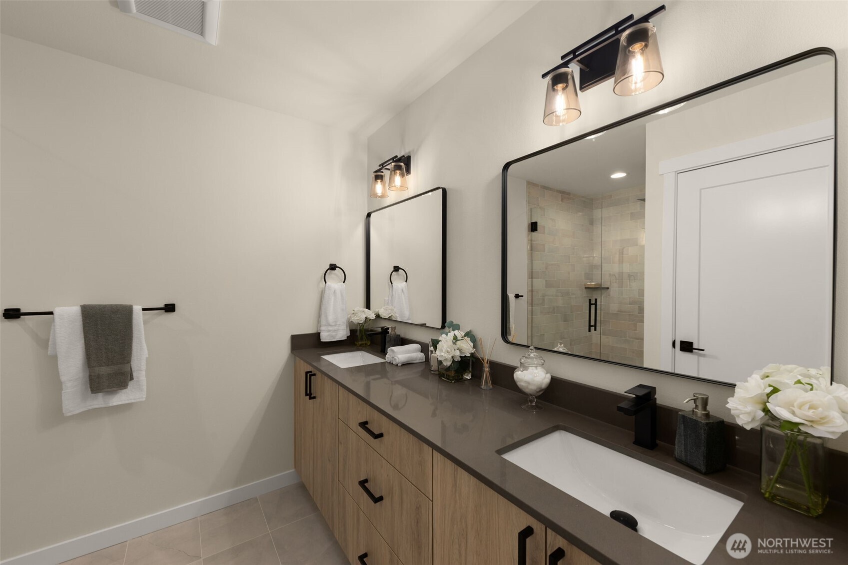 The primary bath feels like a five-star spa! Complete with sleek dual vanities, contemporary lighting, and a soothing palette of stone and glass.