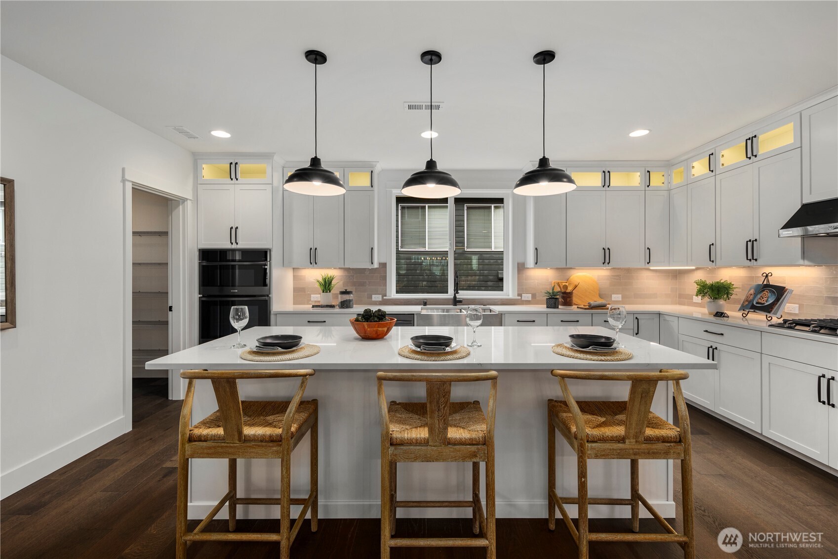 Kitchen Island with Pantry View: Large center island with pendant lighting provides seating and storage while overlooking the walk-in pantry. Perfect for hosting, this layout keeps everything within easy reach.    Photos are from THIS model home at Foxmoore but are for visualization purposes only.  Photos are from the model home at Foxmoore and for visualization purposes only. Plans, colors, building orientation, finishes, home outlook, and other details can and WILL vary.